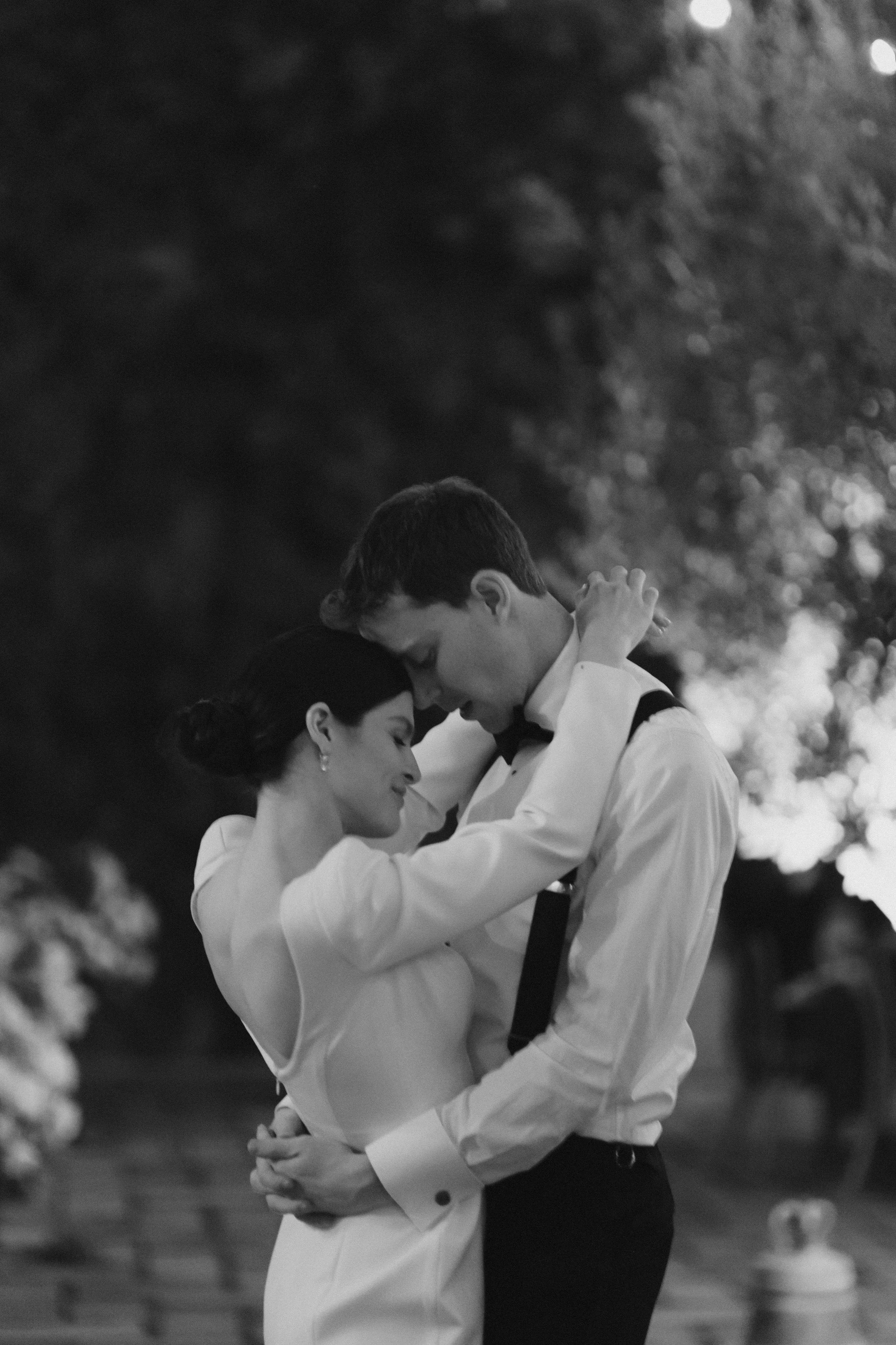Una pareja bailando en un entorno al aire libre, en un momento romántico y tierno, en blanco y negro.
