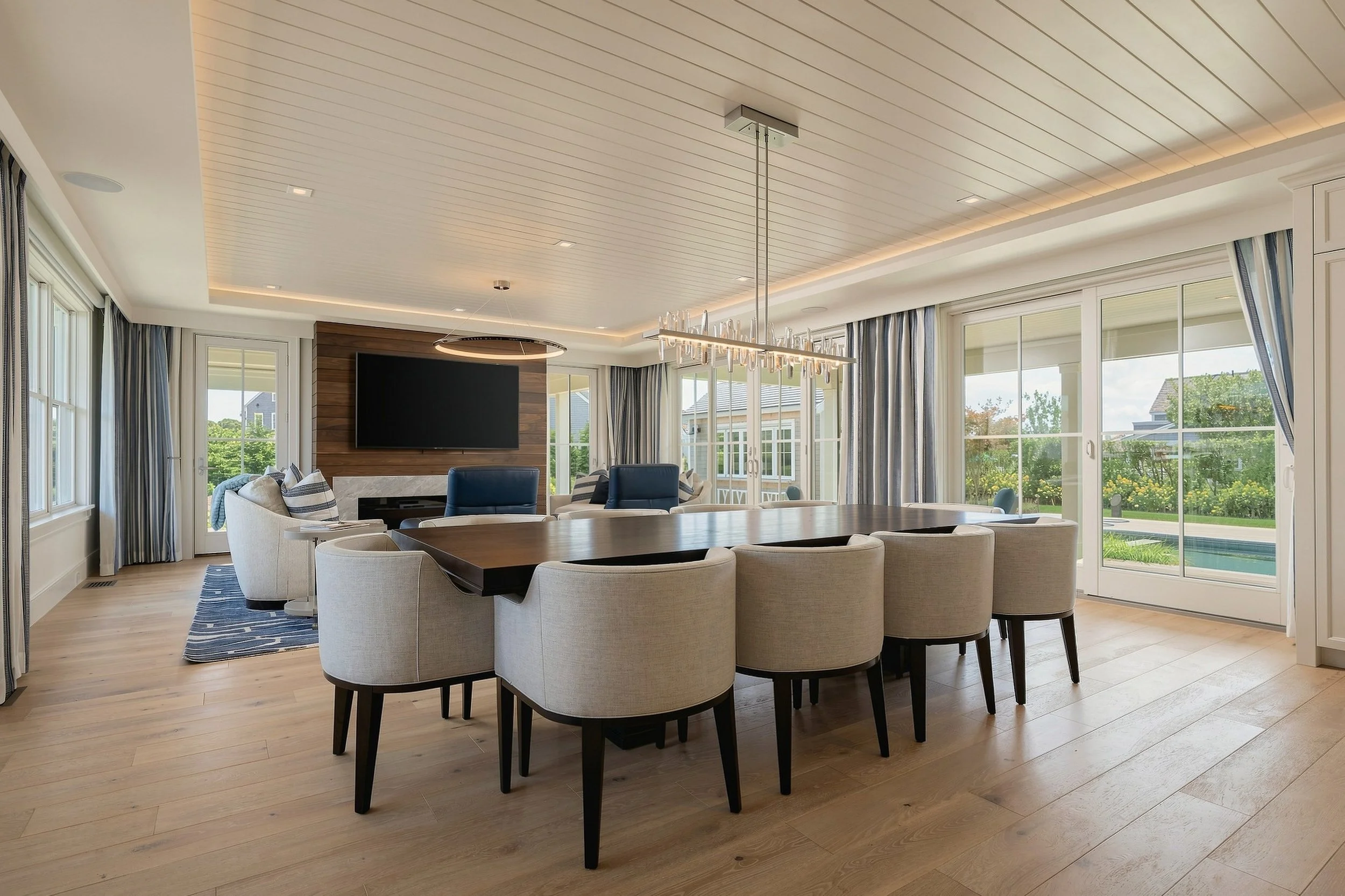 Open dining and living room with a dark wood table, upholstered chairs and full-height garden doors