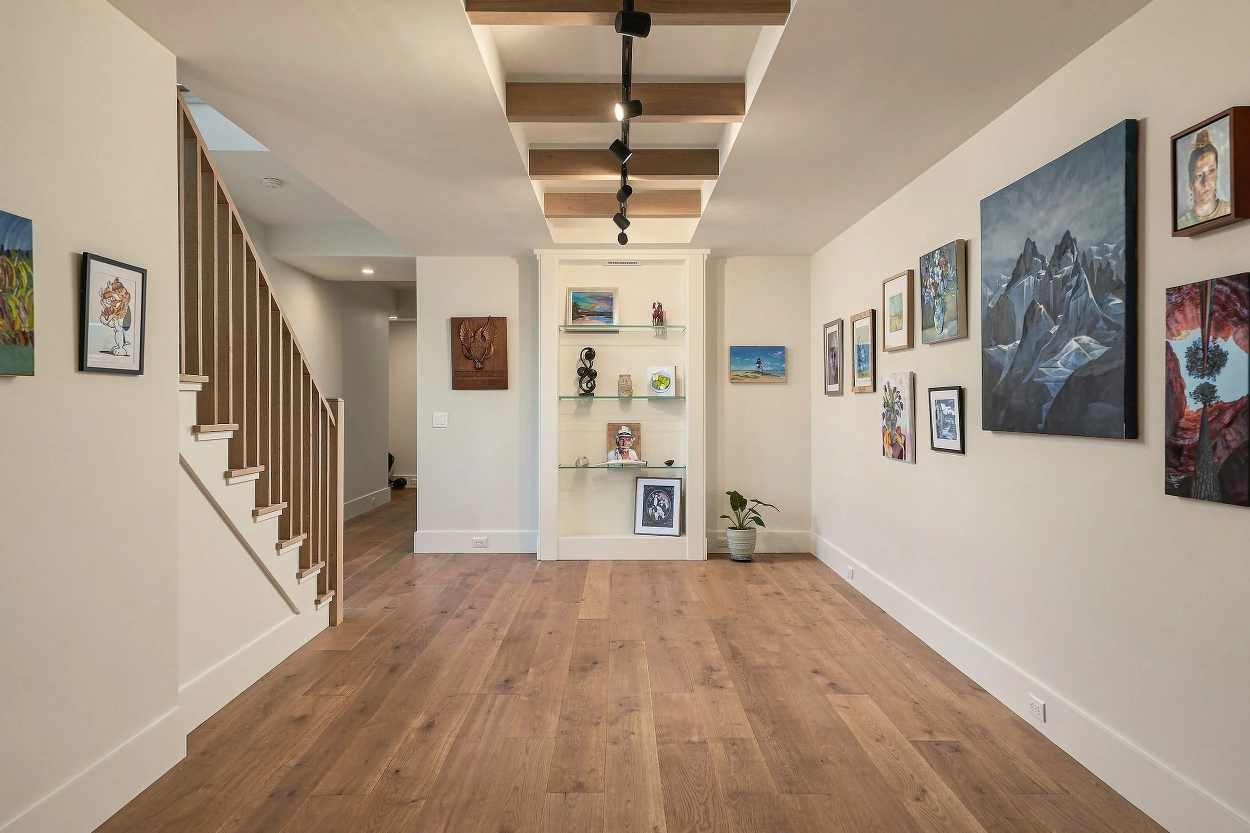 Gallery hallway with oak flooring, wood ceiling beams and a collection of colorful artwork
