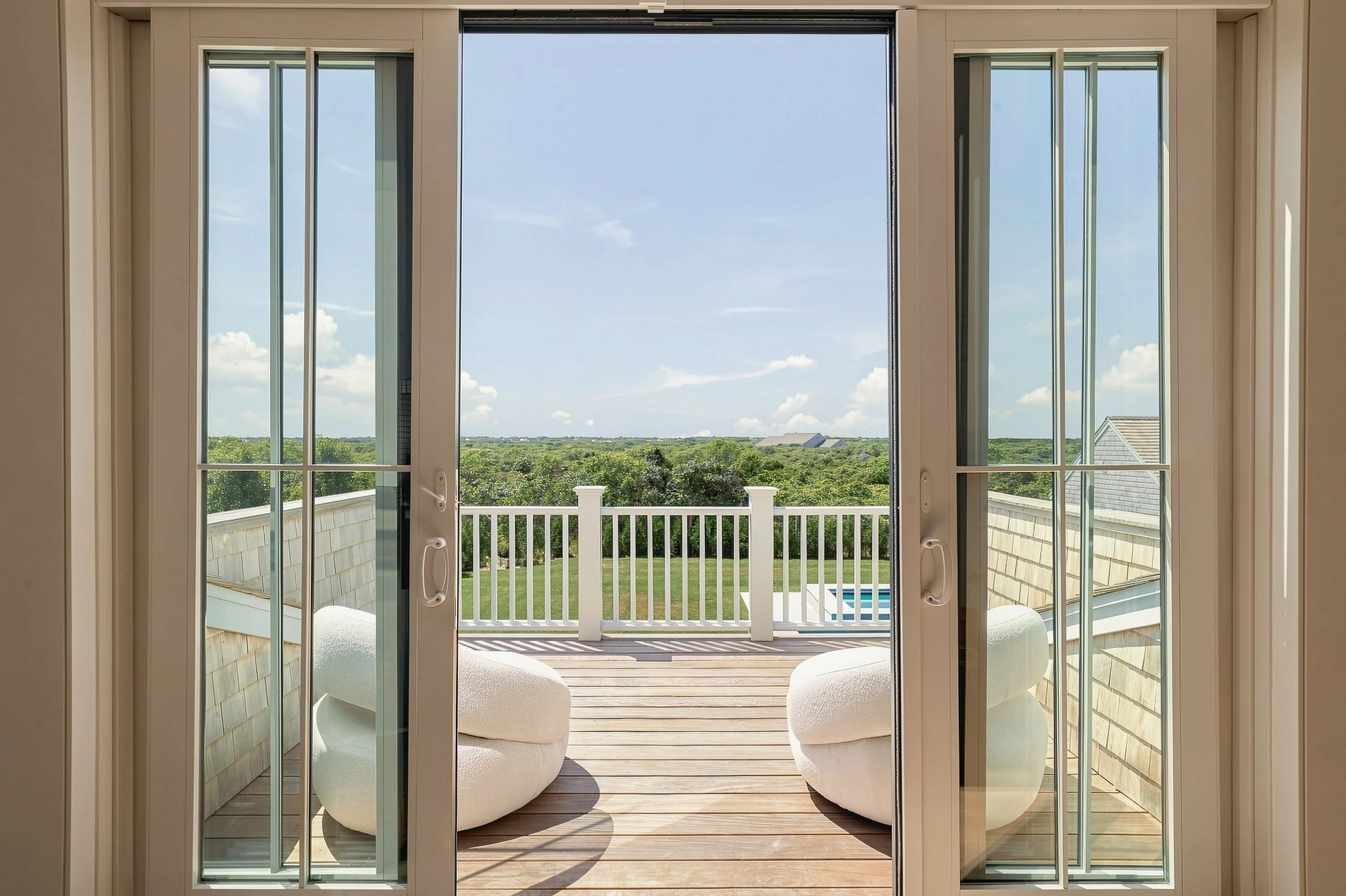 Glass doors opening to a private balcony overlooking the pool and Nantucket landscape