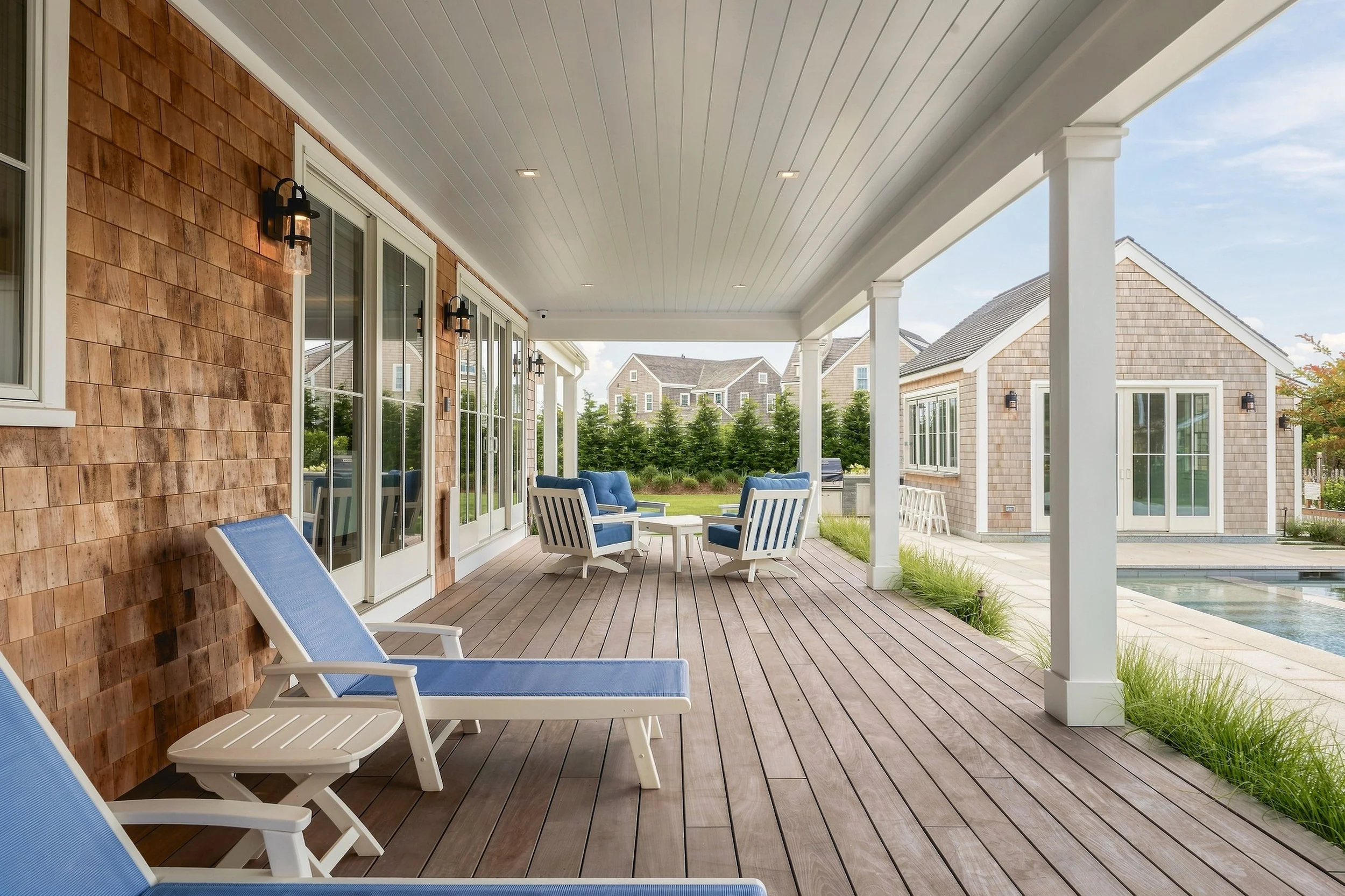 Covered porch with blue lounge seating overlooking the swimming pool and pool house  10-web-or-mls-TRA09167_DTE.jpg