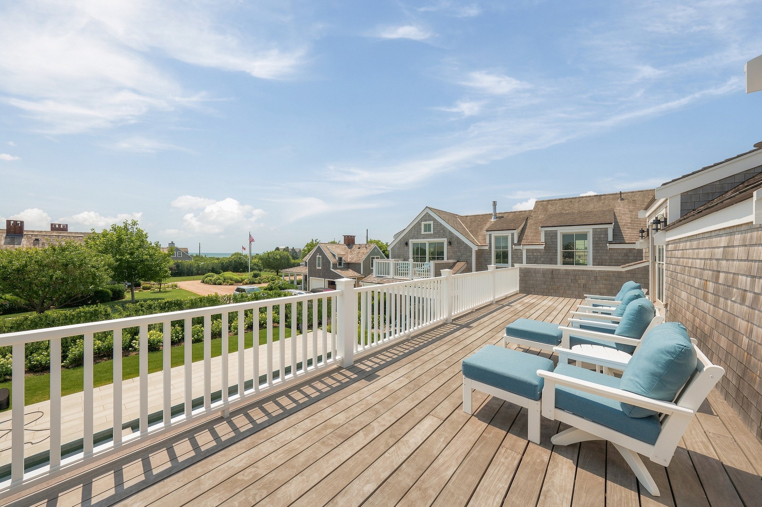 Upper roof deck with blue lounge chairs overlooking the pool and neighboring Nantucket homes