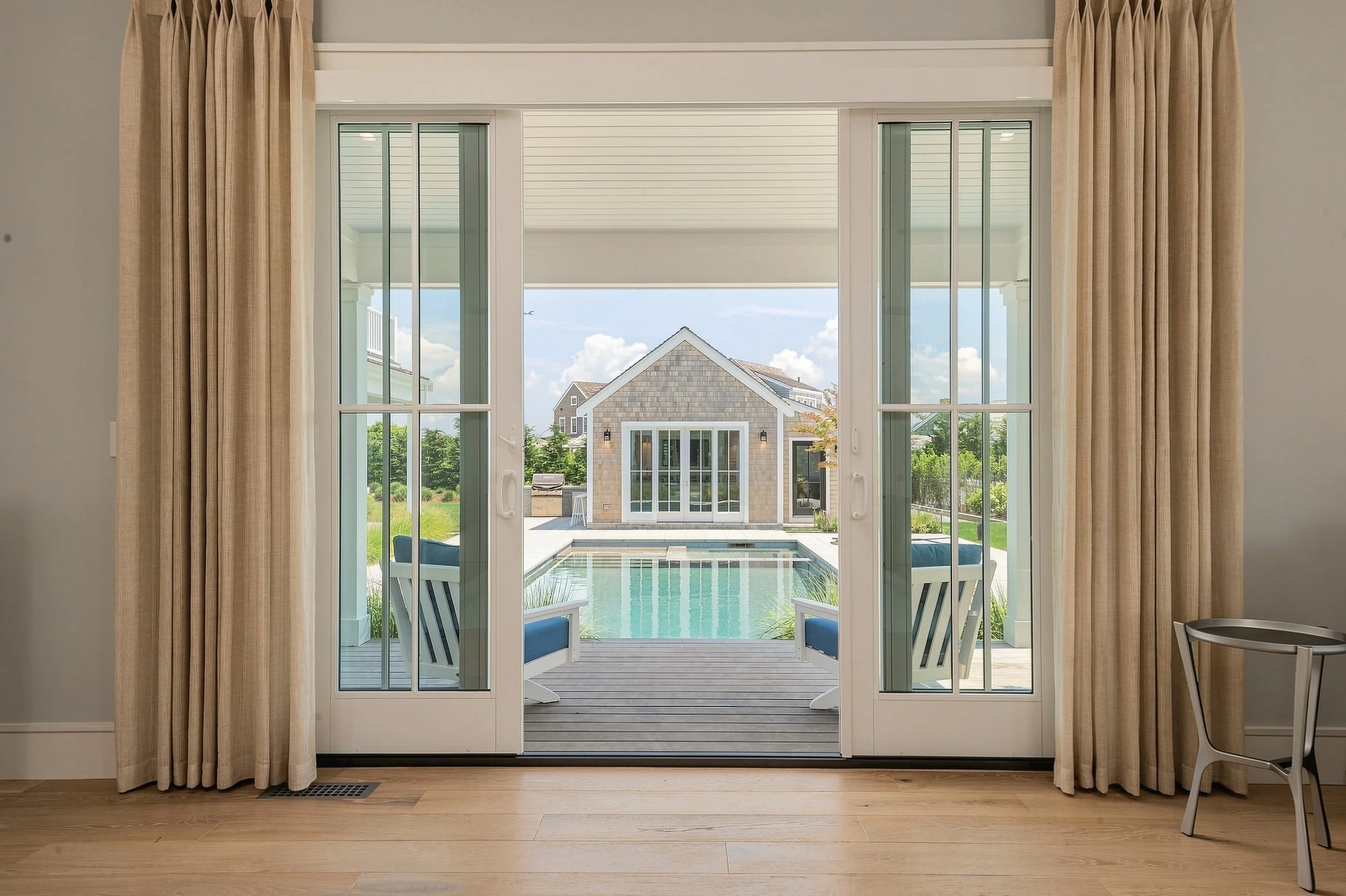 Bedroom doors opening to a covered porch, swimming pool and cedar-shingle pool house