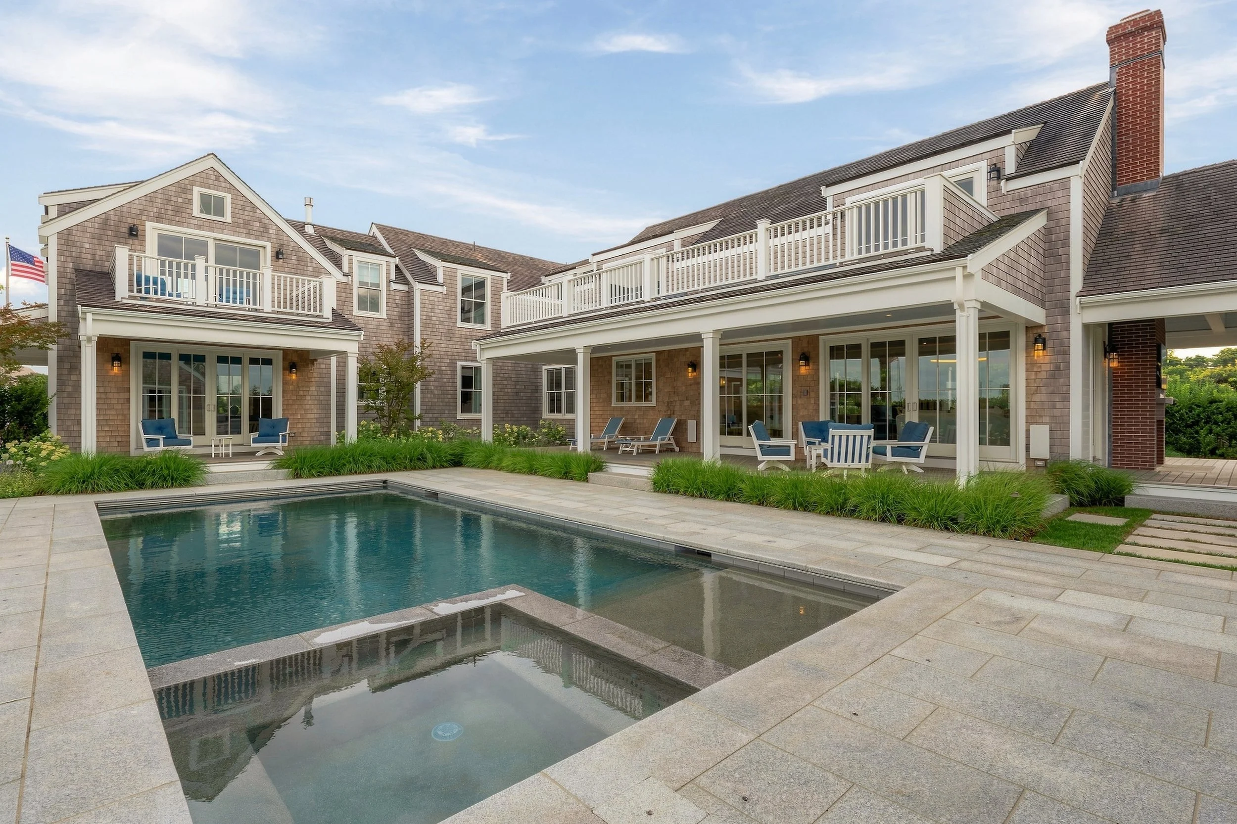 Rear elevation of the cedar-shingle residence with balconies, covered porches, a swimming pool and spa