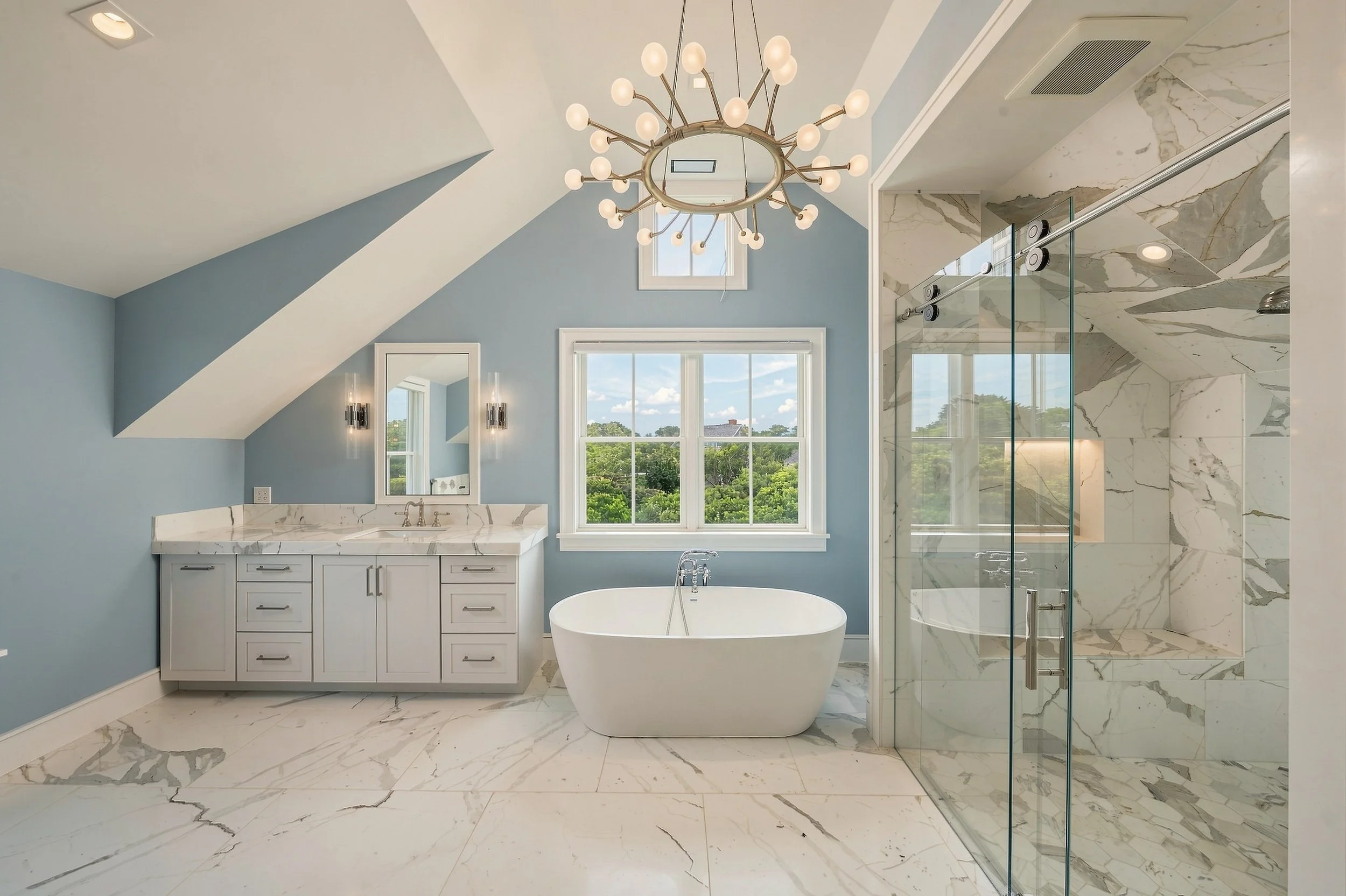 Spacious bathroom with a freestanding tub, marble shower, double vanity and pale blue walls