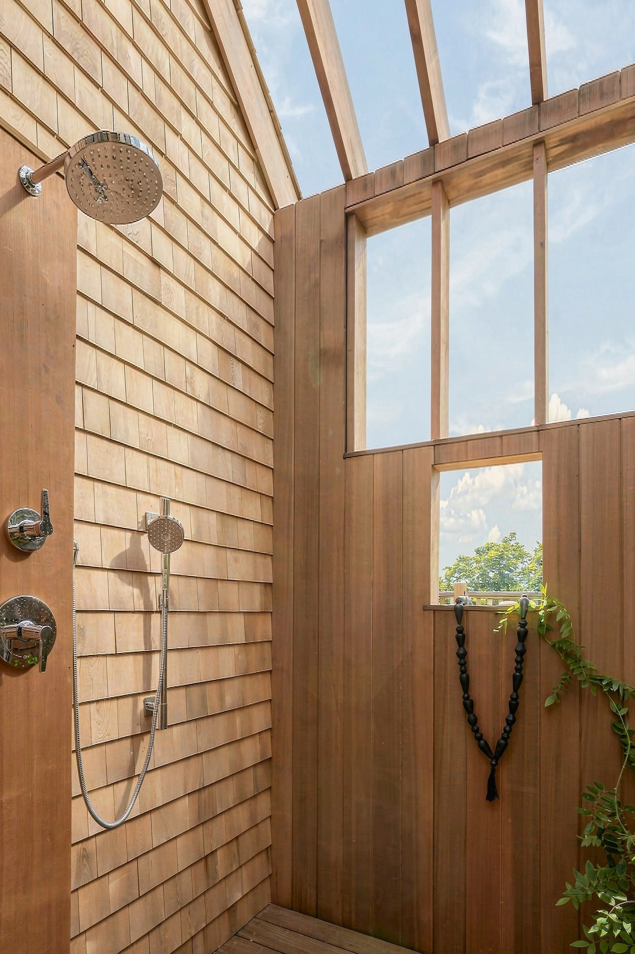 Cedar-lined outdoor shower with a rainfall fixture and open roof beams