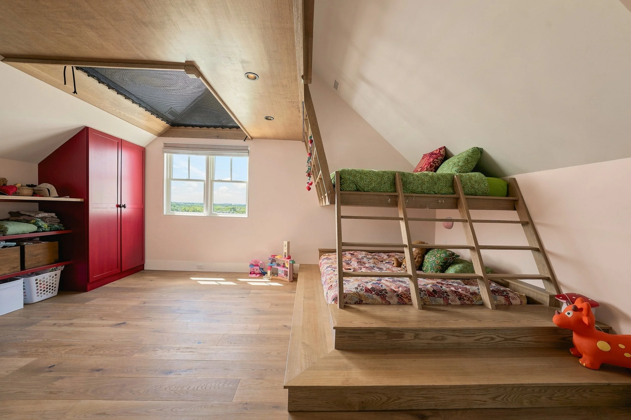 Children’s bunk room with built-in wood beds, pink walls and bright magenta cabinetry