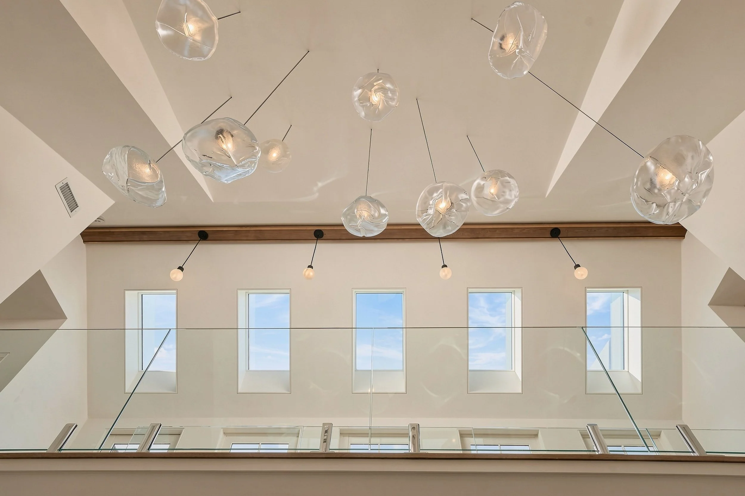 Vaulted entry ceiling with five windows, a wood track light and translucent pendant lights