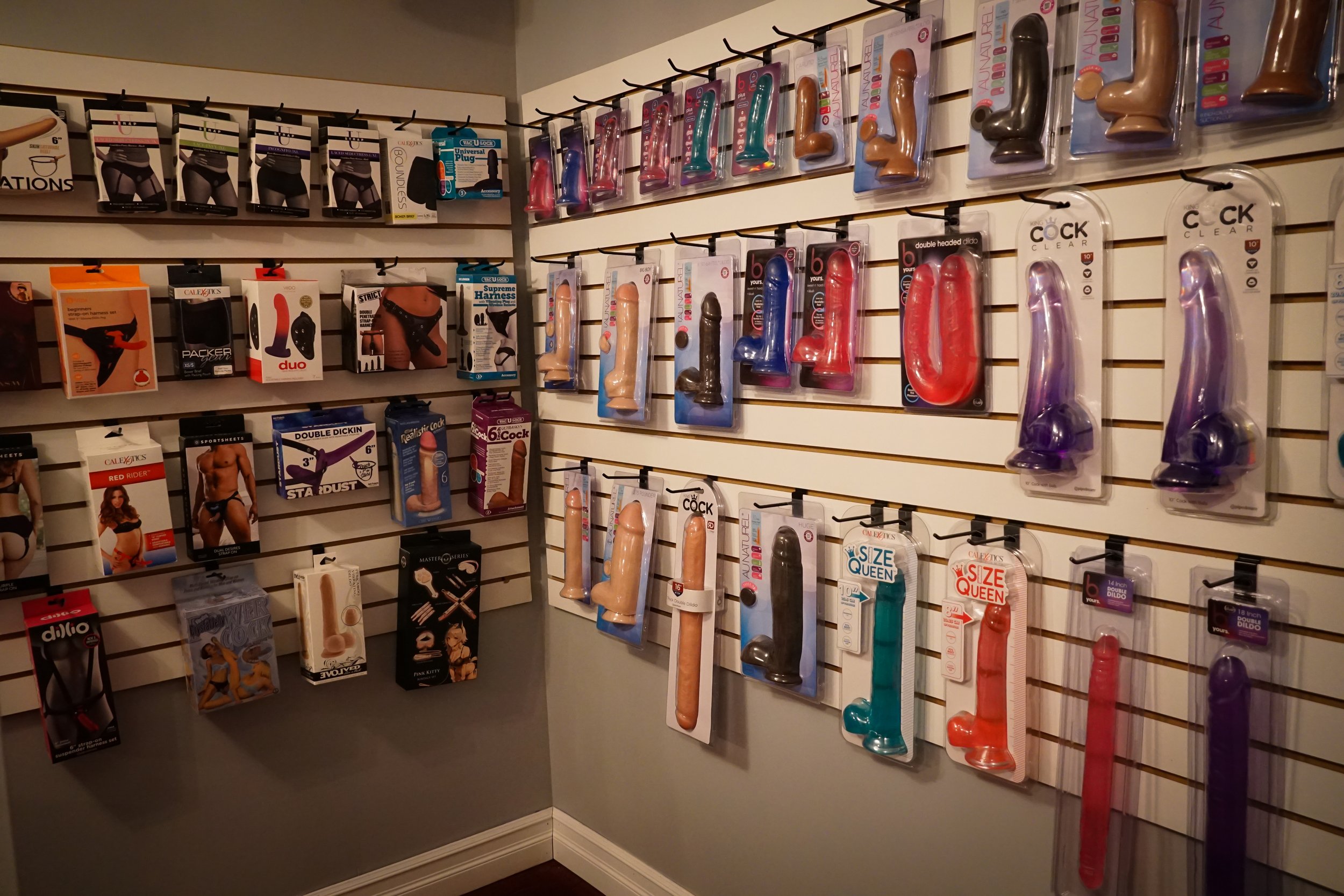 A wall display of various sex toys, including vibrators and dildos, in a retail store.