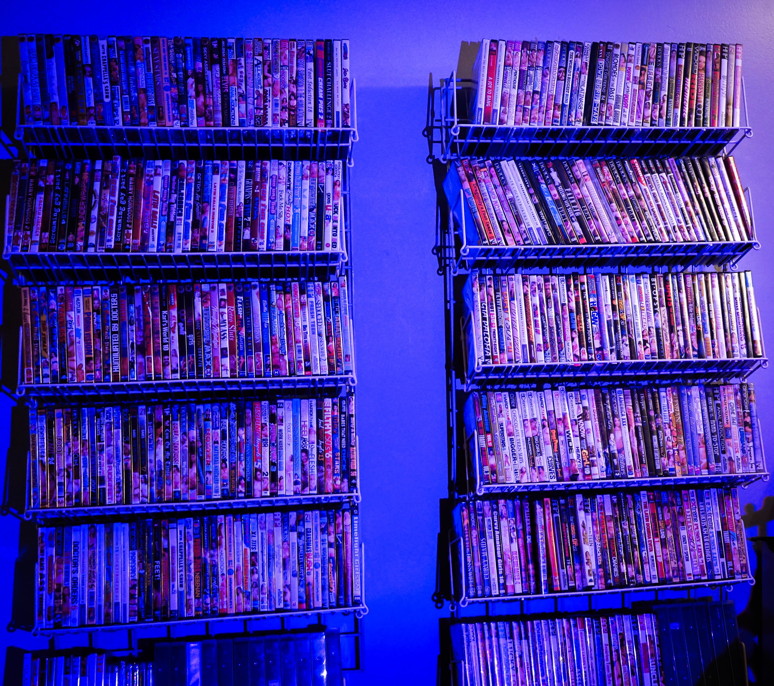 Shelves filled with DVD movies illuminated by blue lighting.