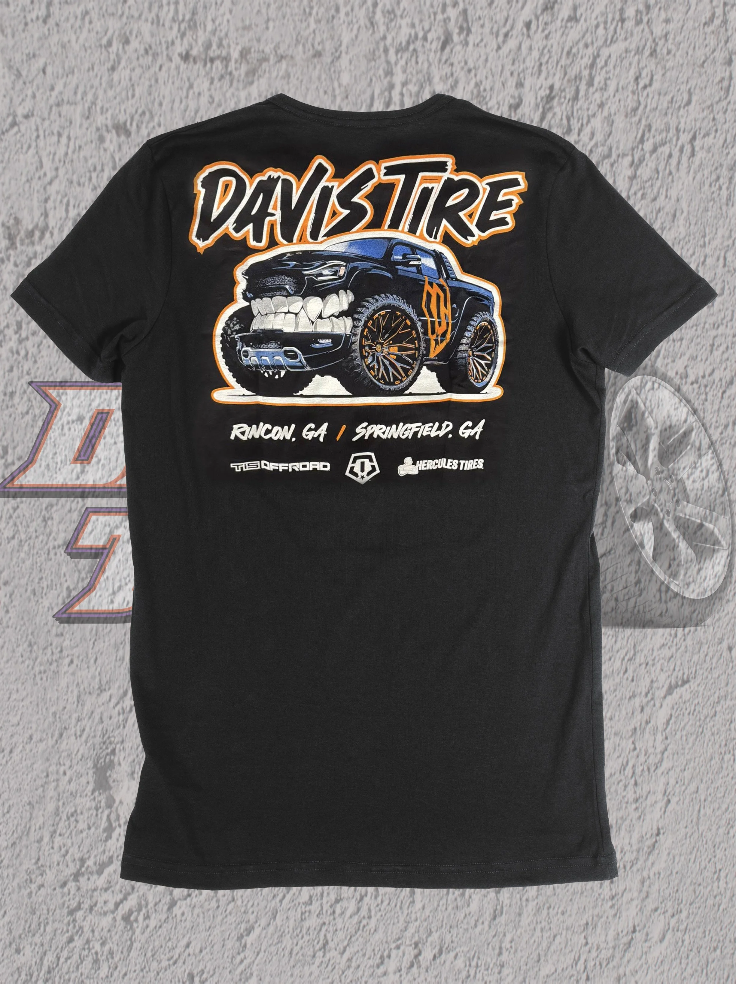 Black T-shirt with graphic design of a modified pickup truck with large wheels, a grill with teeth, and the word 'DaviStire' in stylized orange and white letters. Below the truck, there are locations Rincon, GA and Springfield, GA. Logos for TIS Offroad, Hercules Tires, and another badge are also visible.