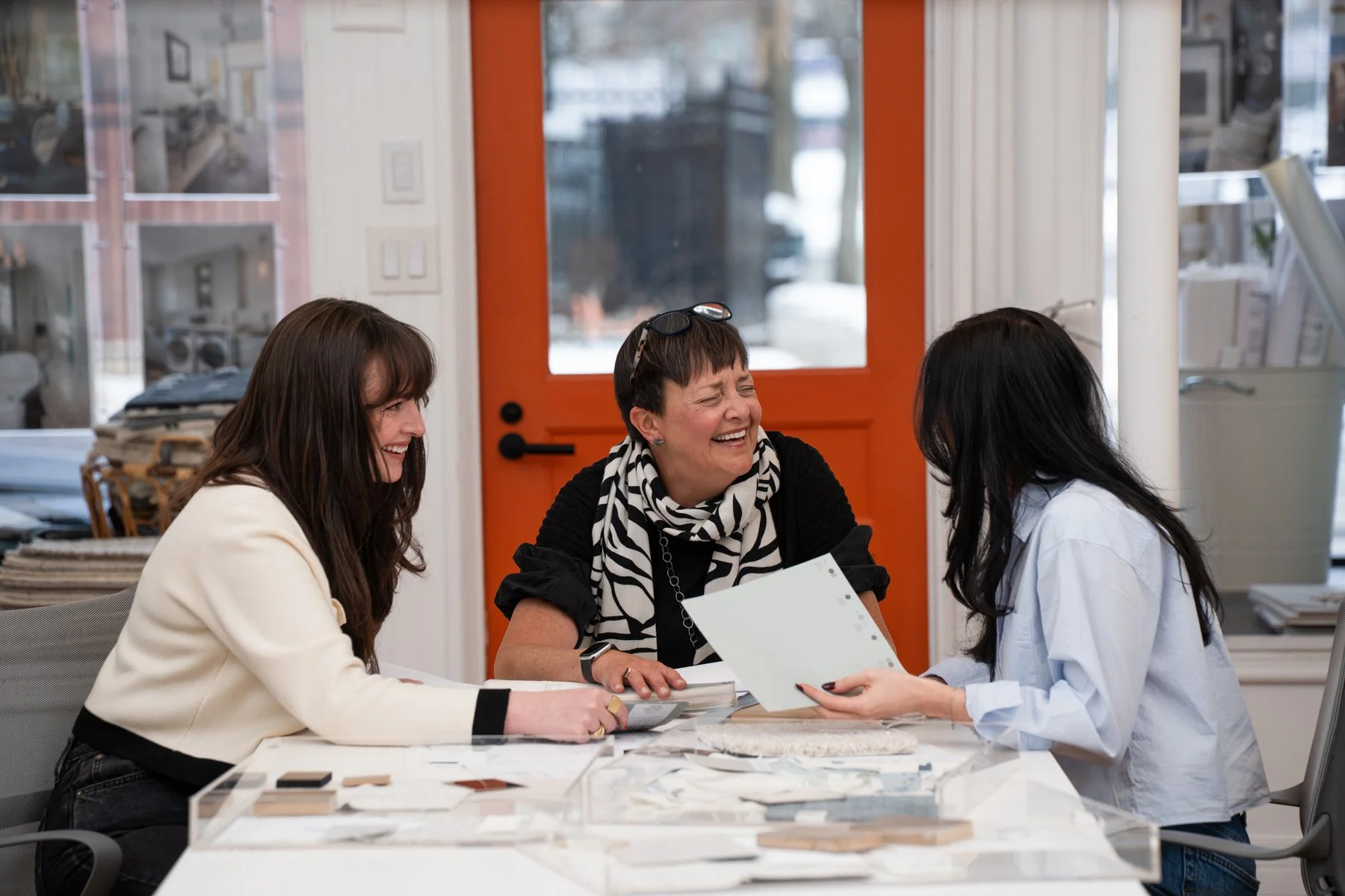 Rocksalt Studio team members sitting at a table in a creative workspace, laughing and discussing design materials on the table.