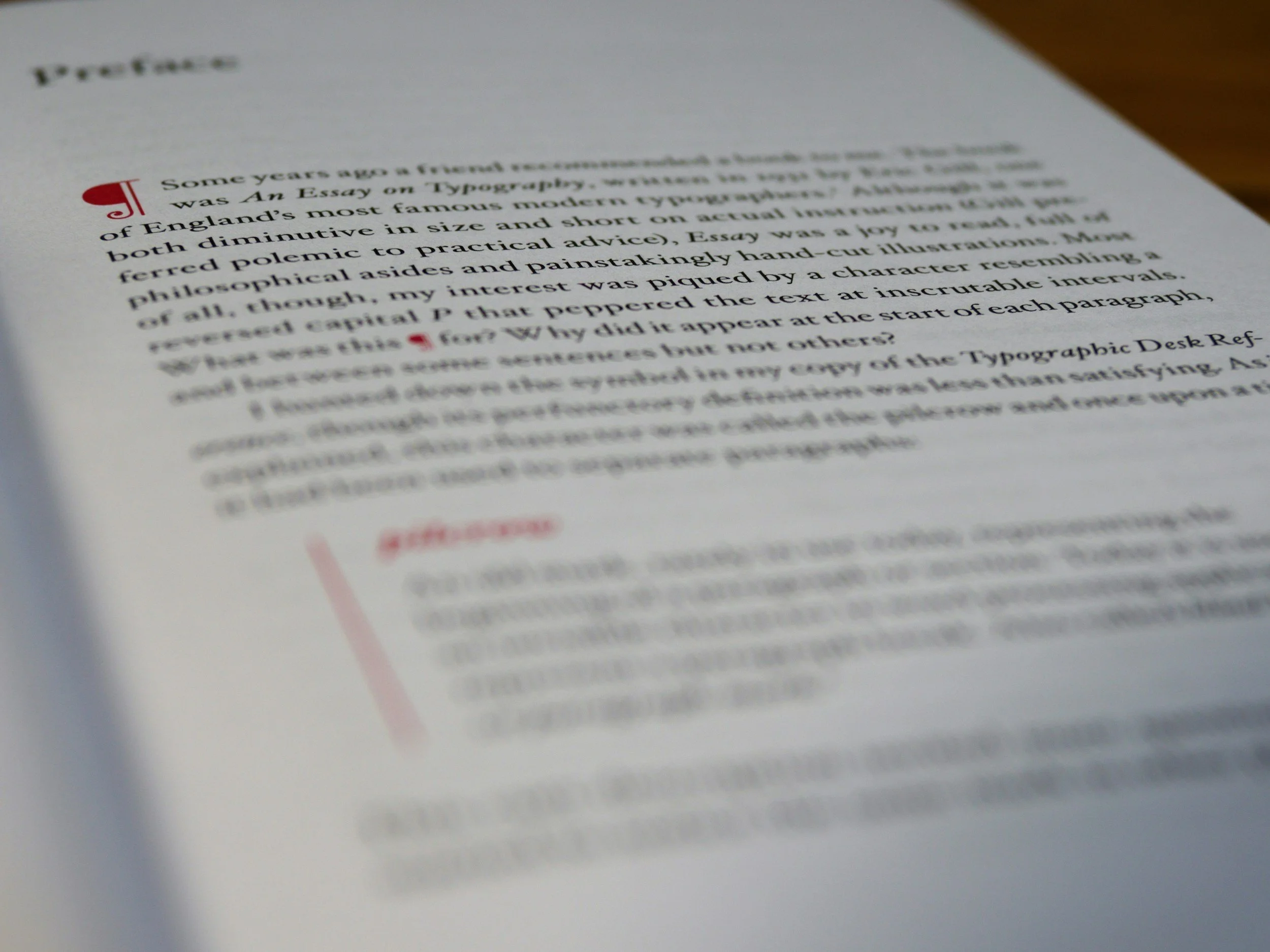 Close-up photograph of a printed page, slightly tilted, with text that is partially blurred, and red highlighted sections.