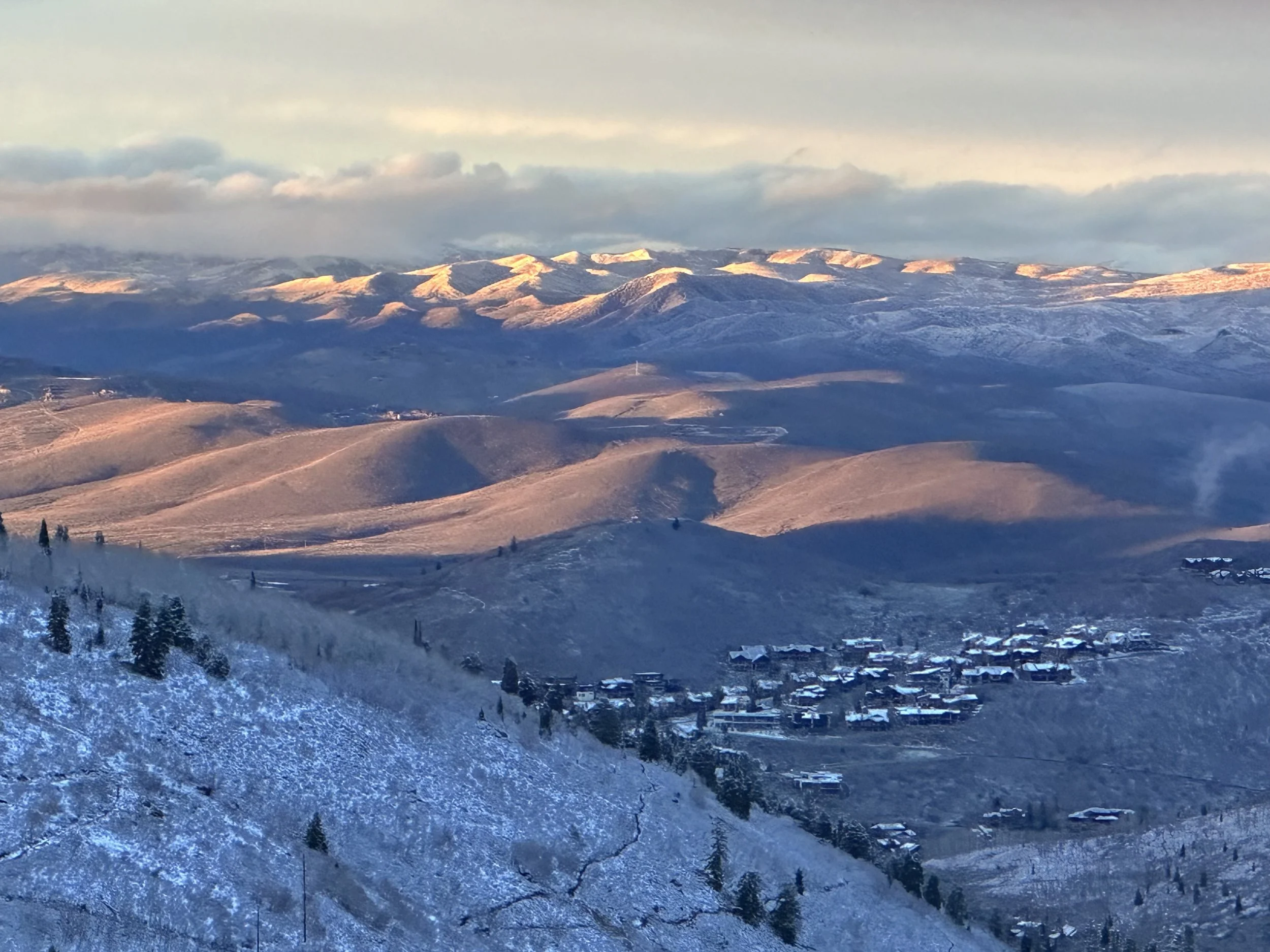 Snow-covered mountains and hills with a small village at the base on a clear day during winter.