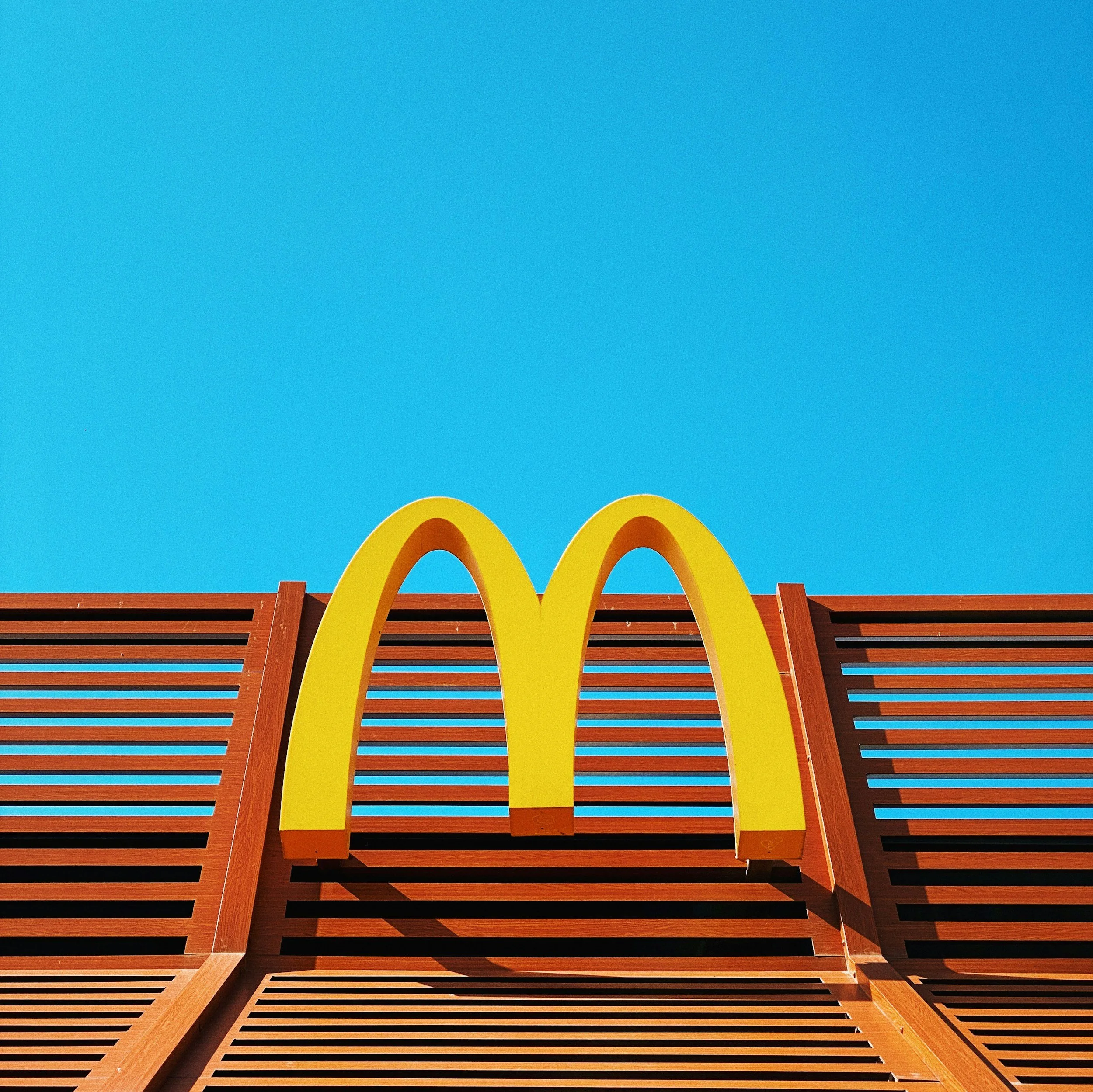 McDonald's logo on a red wooden structure against a bright blue sky.