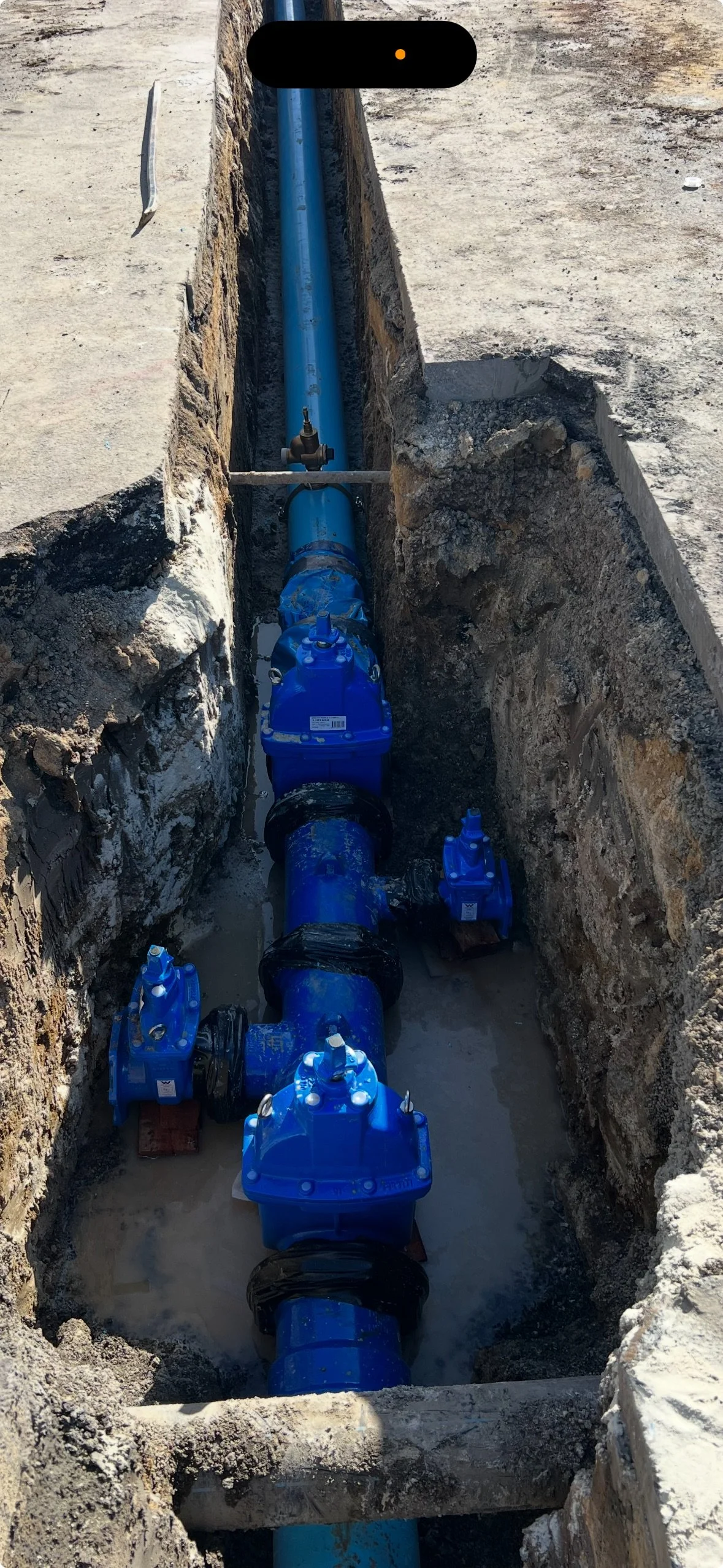 View of a serene lake surrounded by green hills and tall mountains in the background under a cloudy sky.