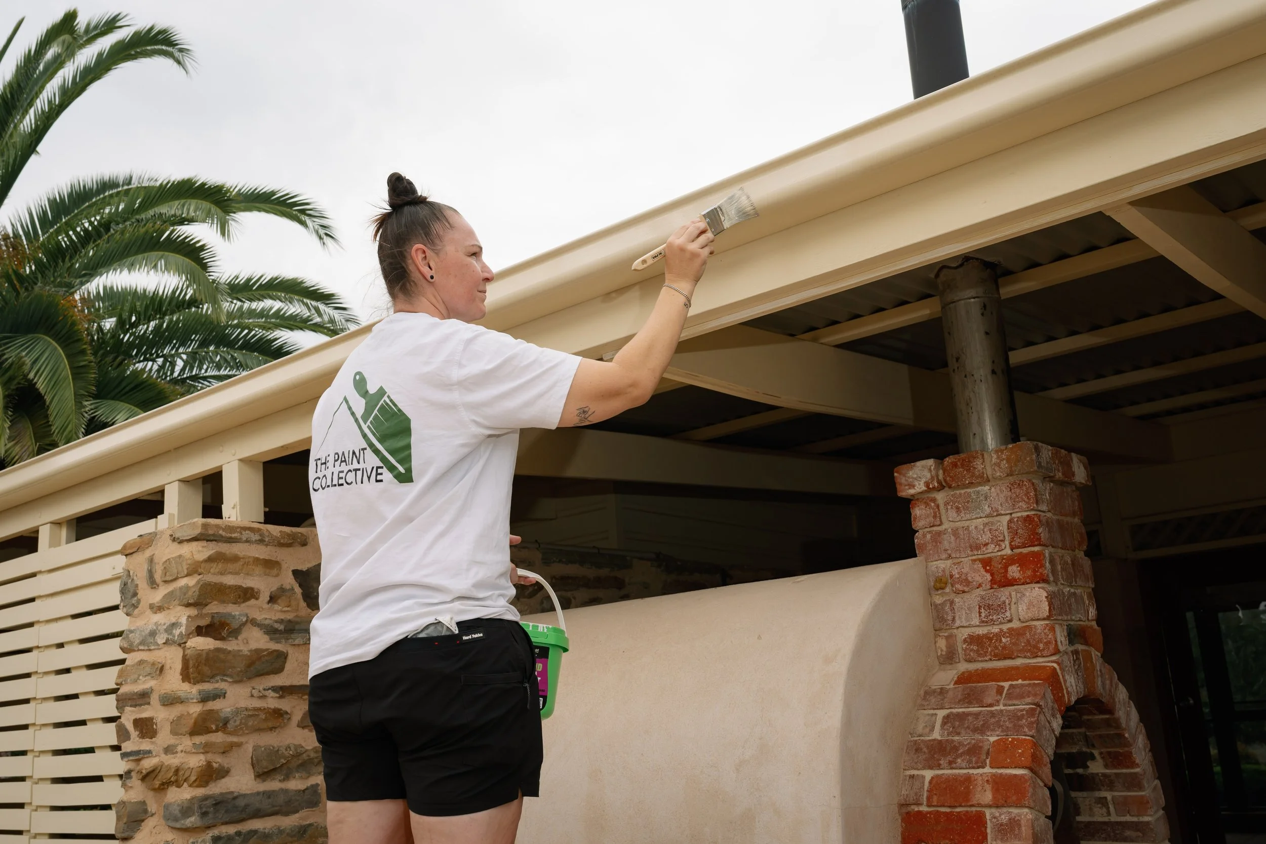 Professional house painter painting exterior roof trim on a residential home.