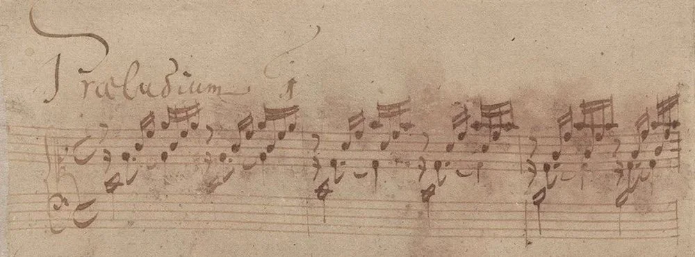 An excerpt from Bach's manuscript of his C major Prelude, showing musical notes and some cursive writing.