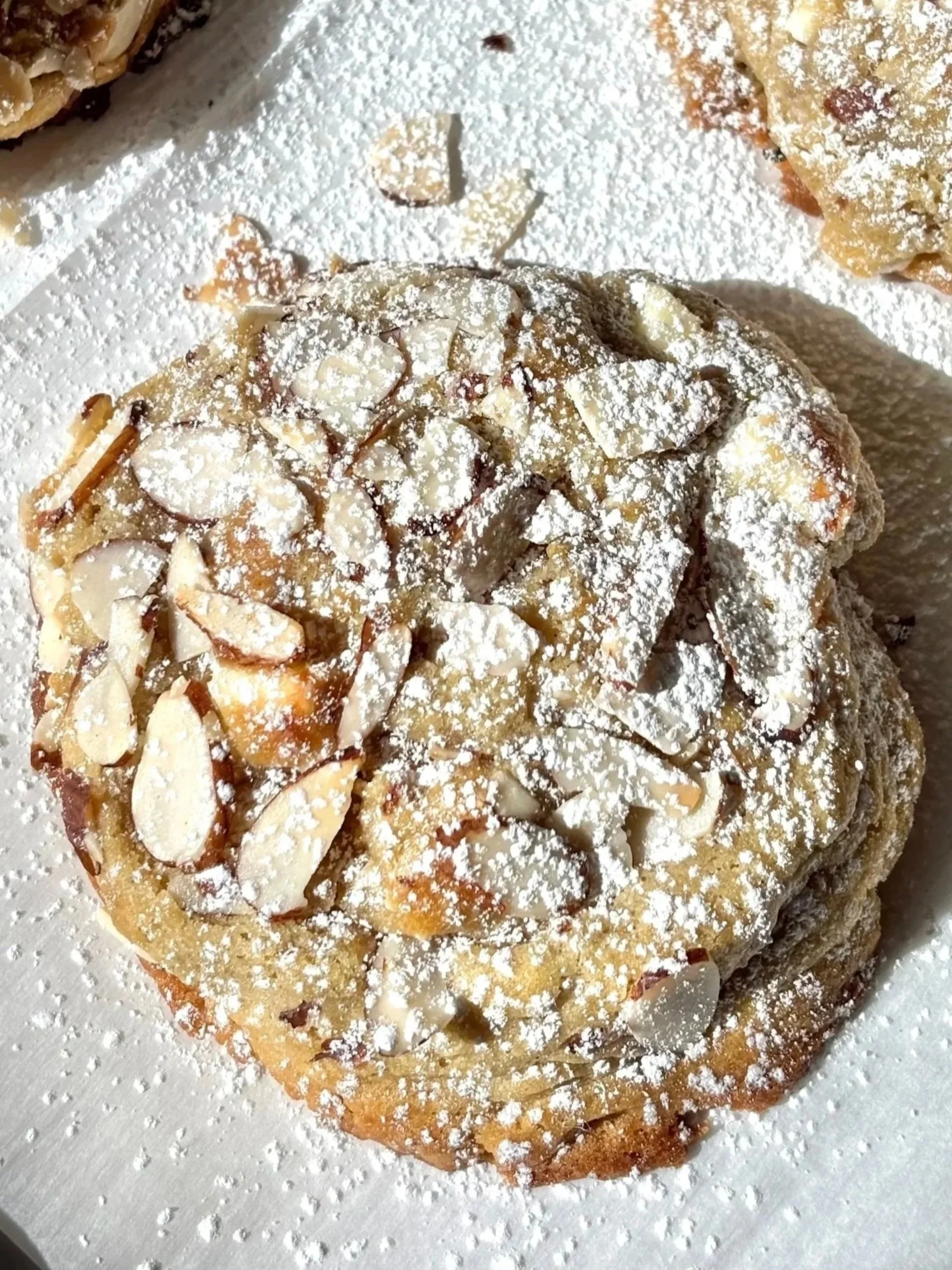 Close up of a cookie topped with almond and powdered sugar