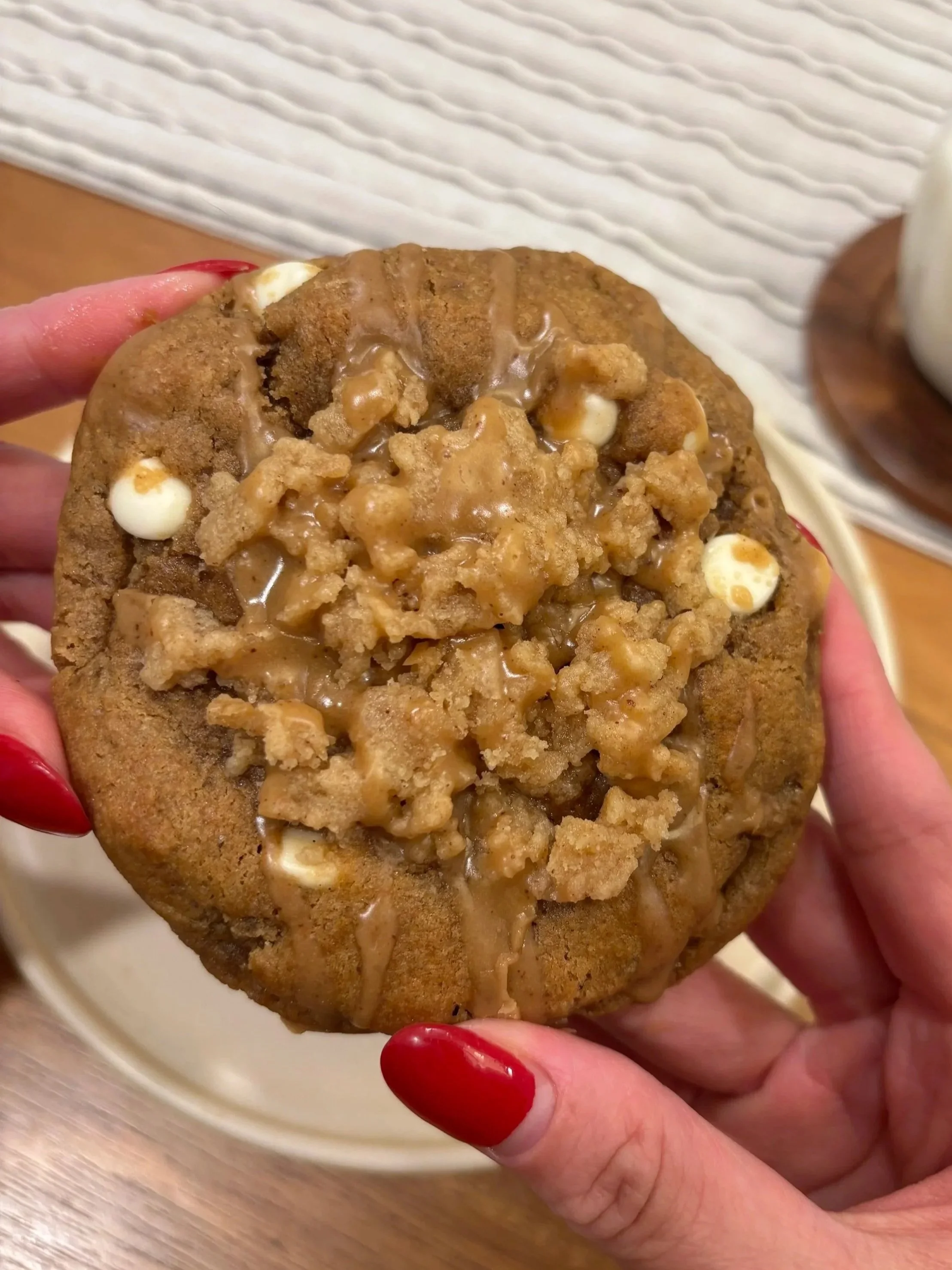 Hand holding a large gingerbread cookie with visible coffeecake streusel on top.