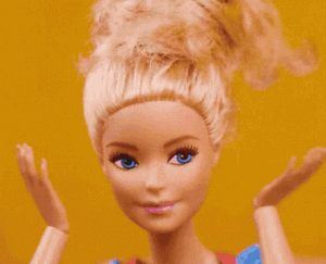 Close-up of a Barbie doll with blonde hair styled in an updo, standing against a yellow background.