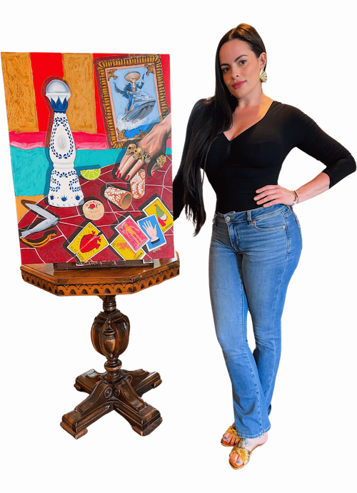 A woman with long dark hair wearing a black top and jeans standing next to a colorful painting on a wooden easel.
