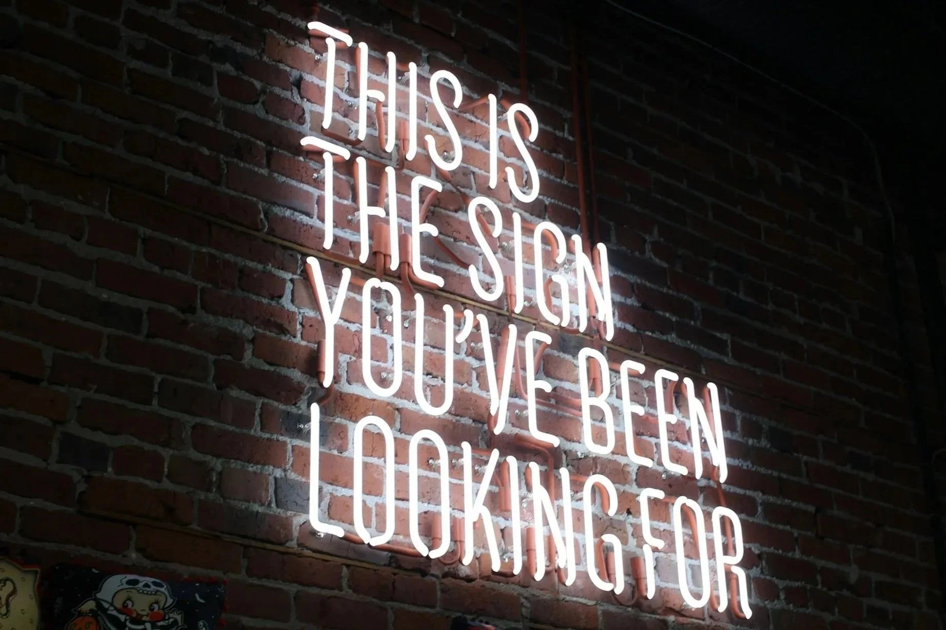 Neon sign on a brick wall reading "This is the step you’ve been waiting for."