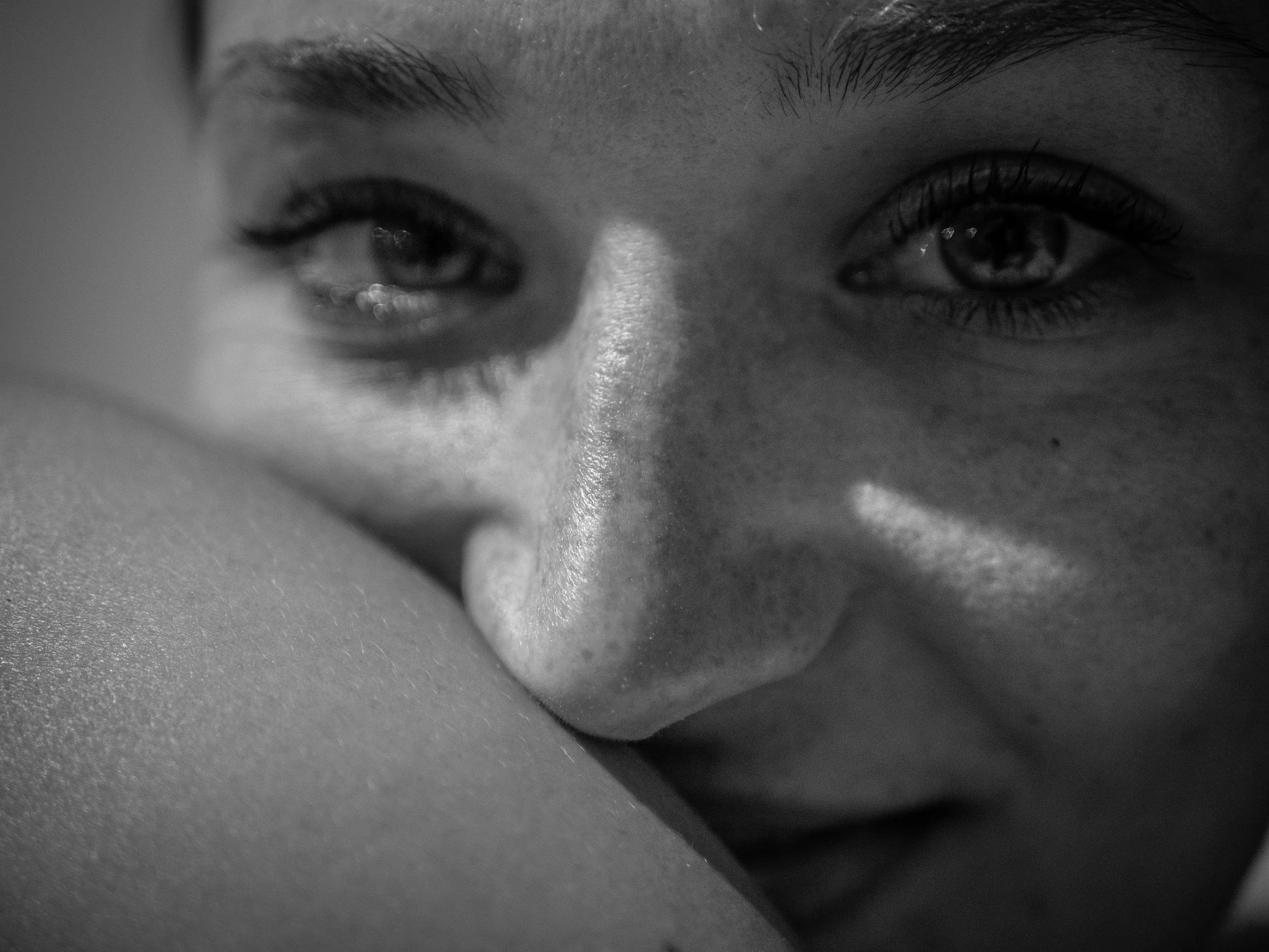 Close-up black and white photograph of a person's face, focusing on the eyes and nose.