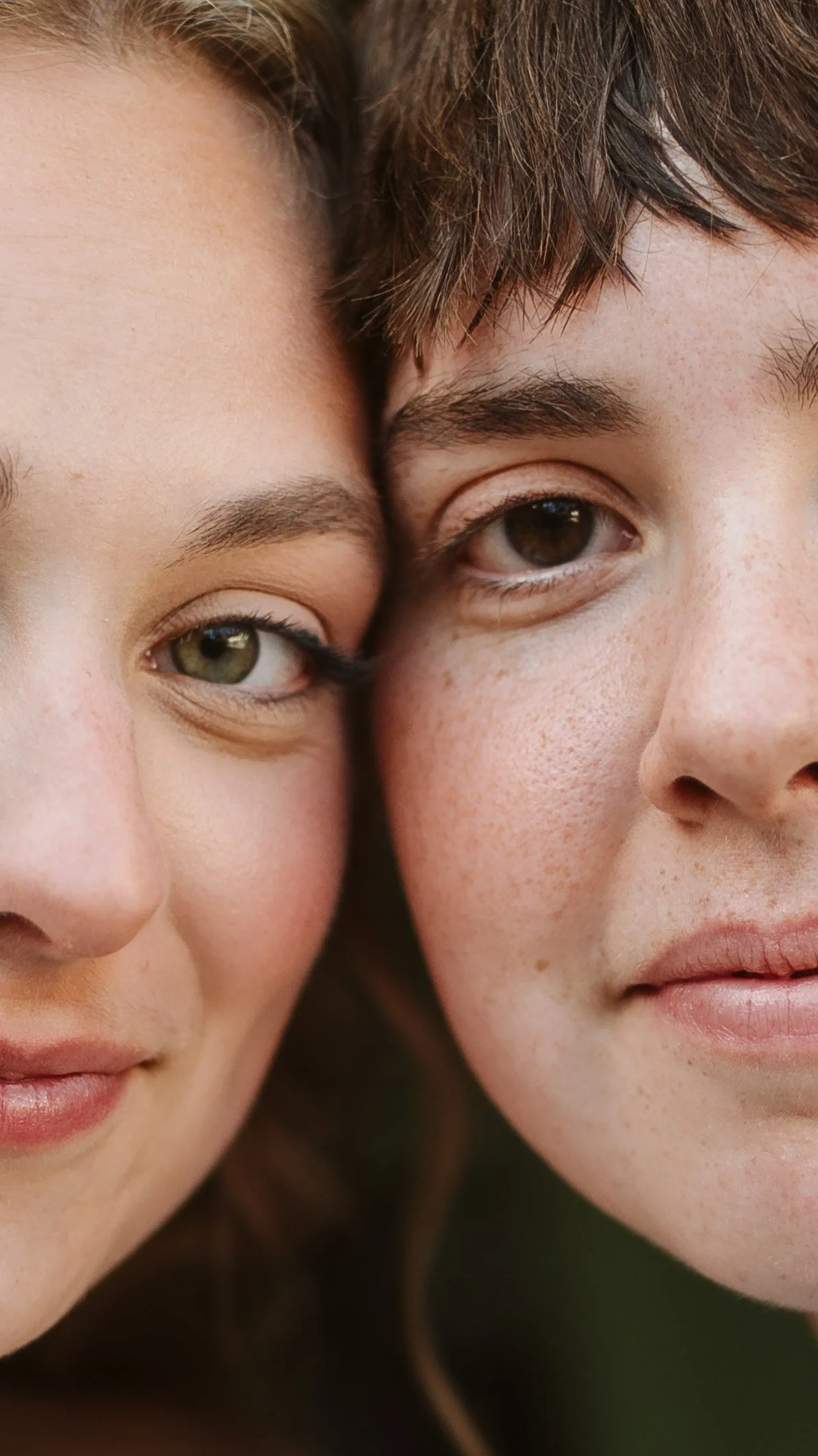 Close-up of two young women with their faces pressed together, showing their eyes, noses, and part of their lips.