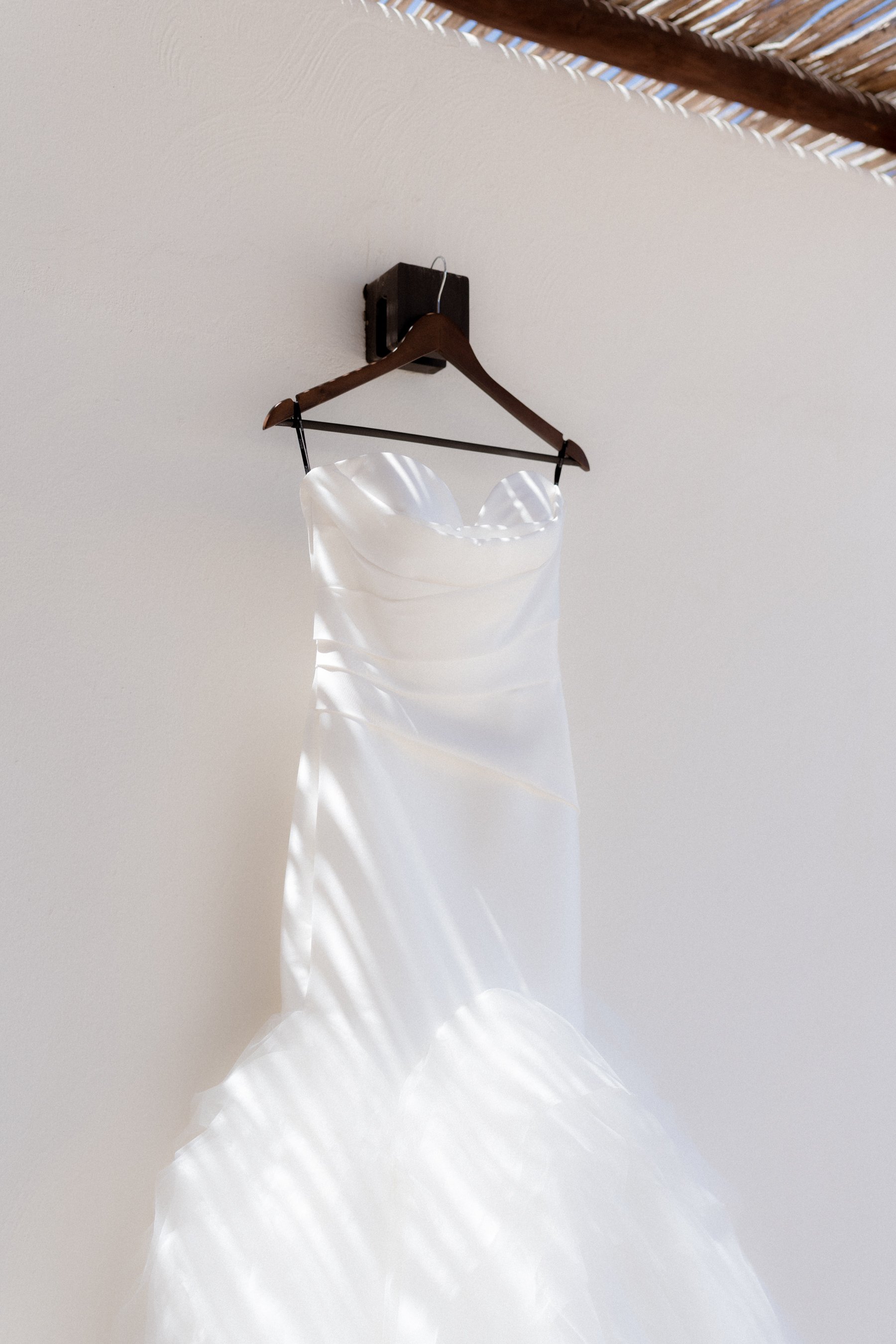Vestido de novia blanco colgado de una percha en el techo.