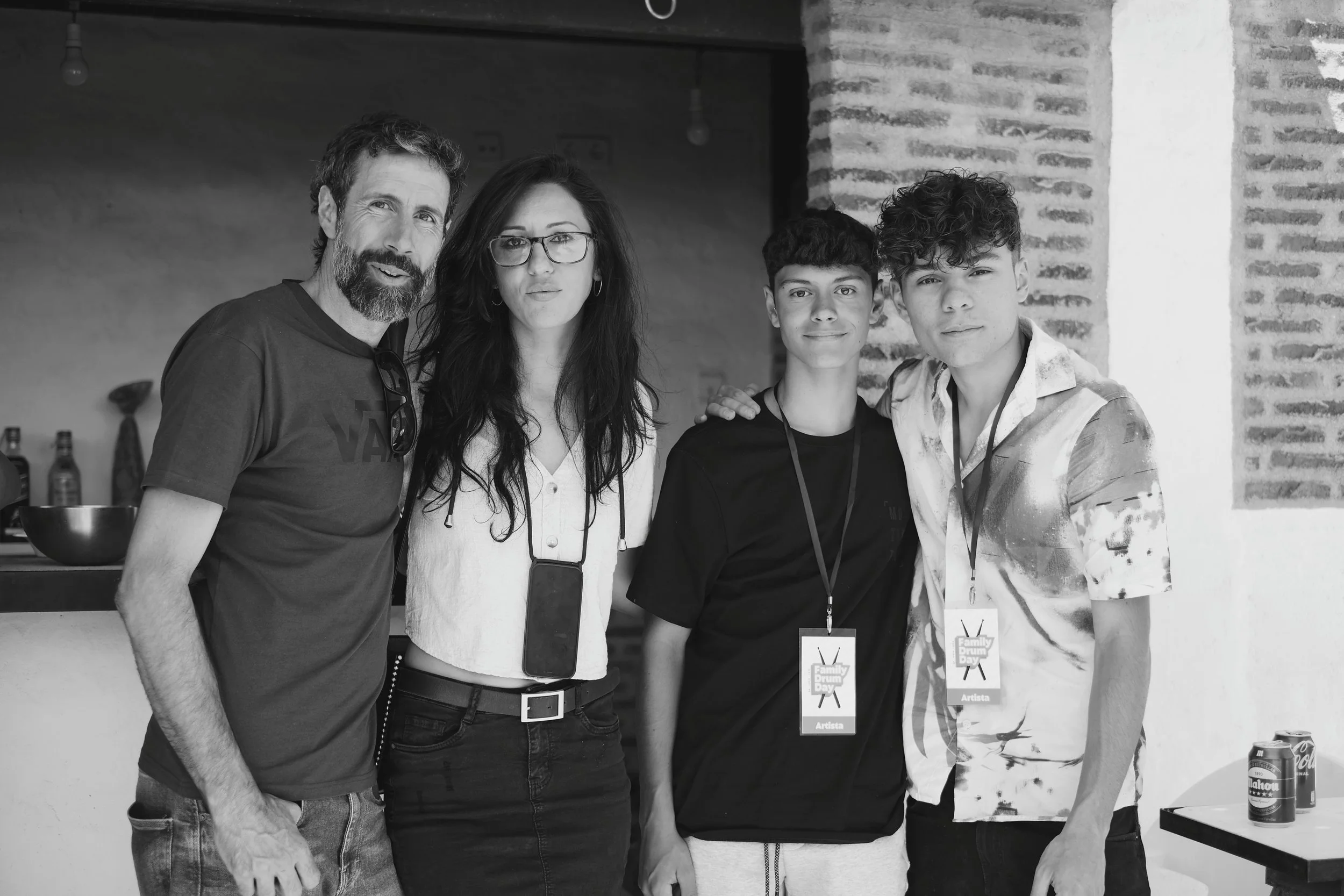 Familia con dos jóvenes en un evento, todos con gafetes de identificación. La imagen es en blanco y negro.