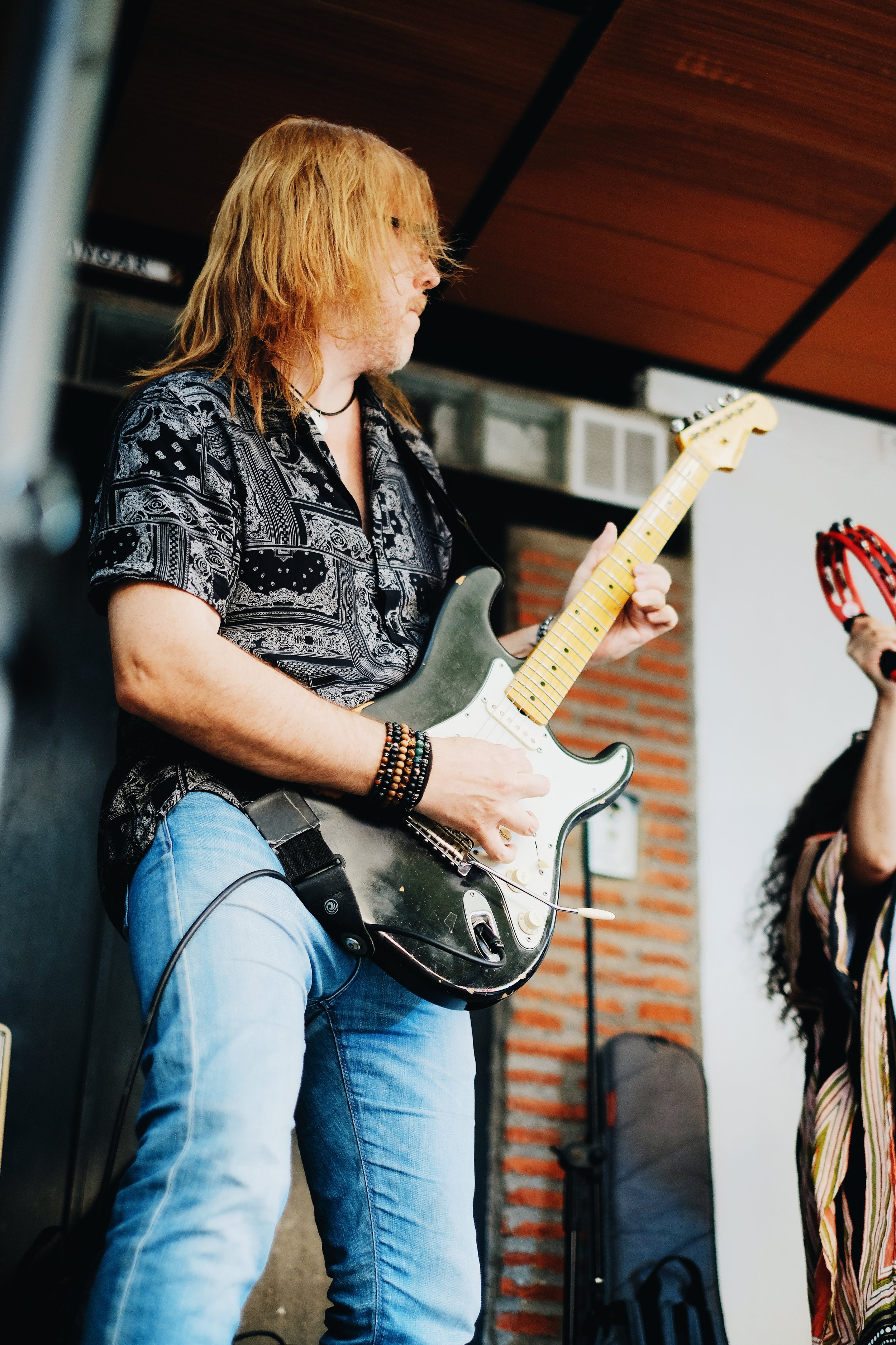 Un hombre tocando la guitarra eléctrica en un escenario.