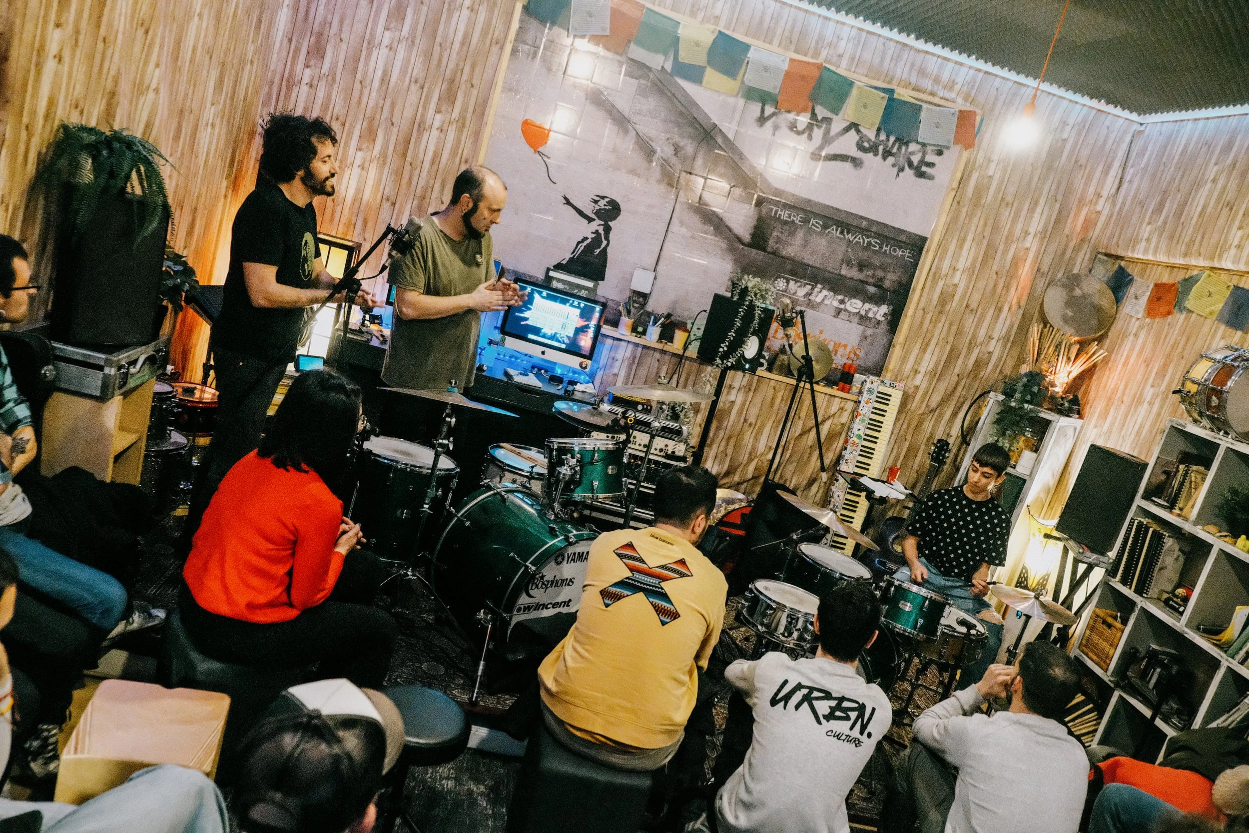 Grupo de músicos tocando en un ambiente interior con paredes de madera y decoraciones artísticas.