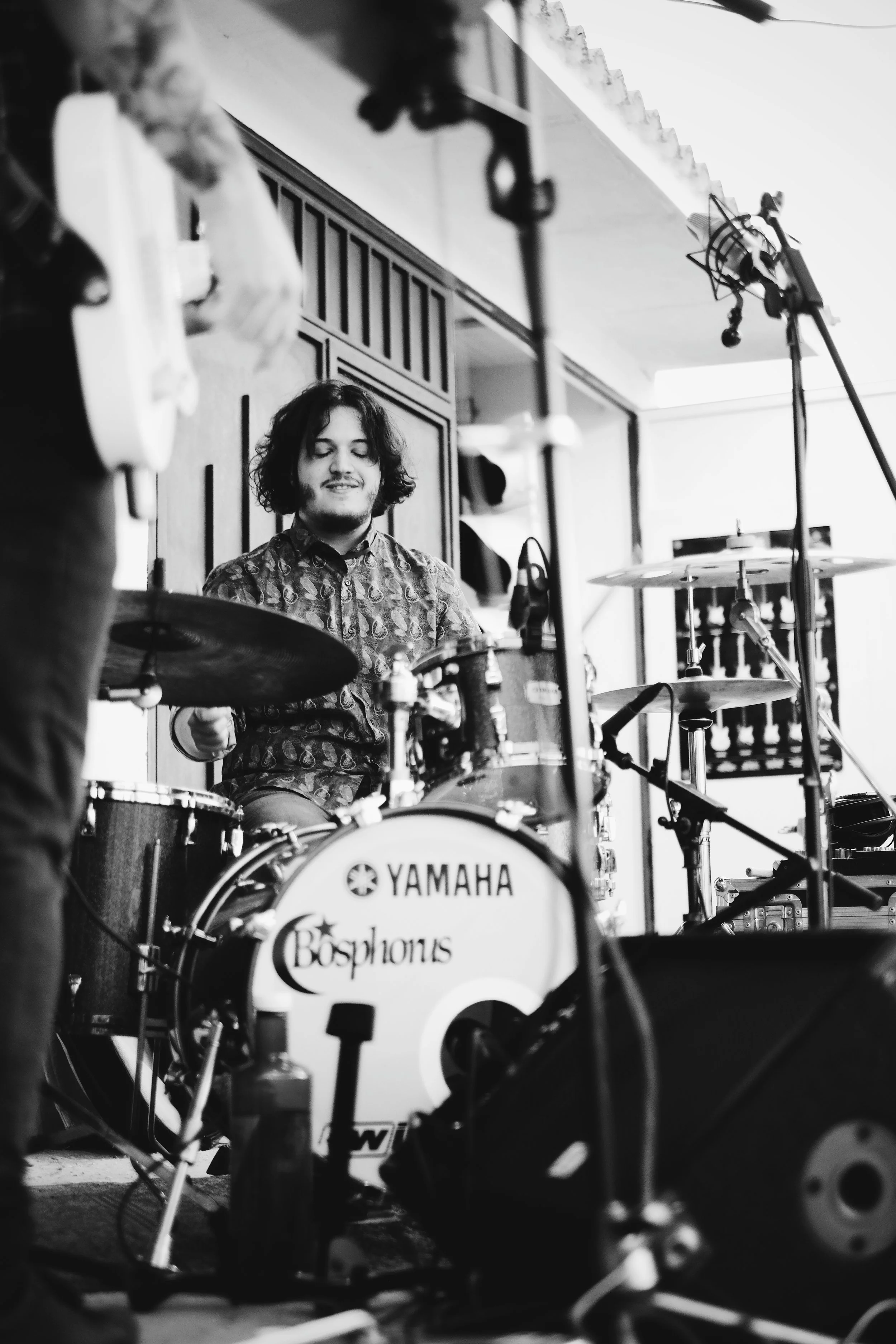 Un joven tocando la batería en un estudio de grabación, en blanco y negro.