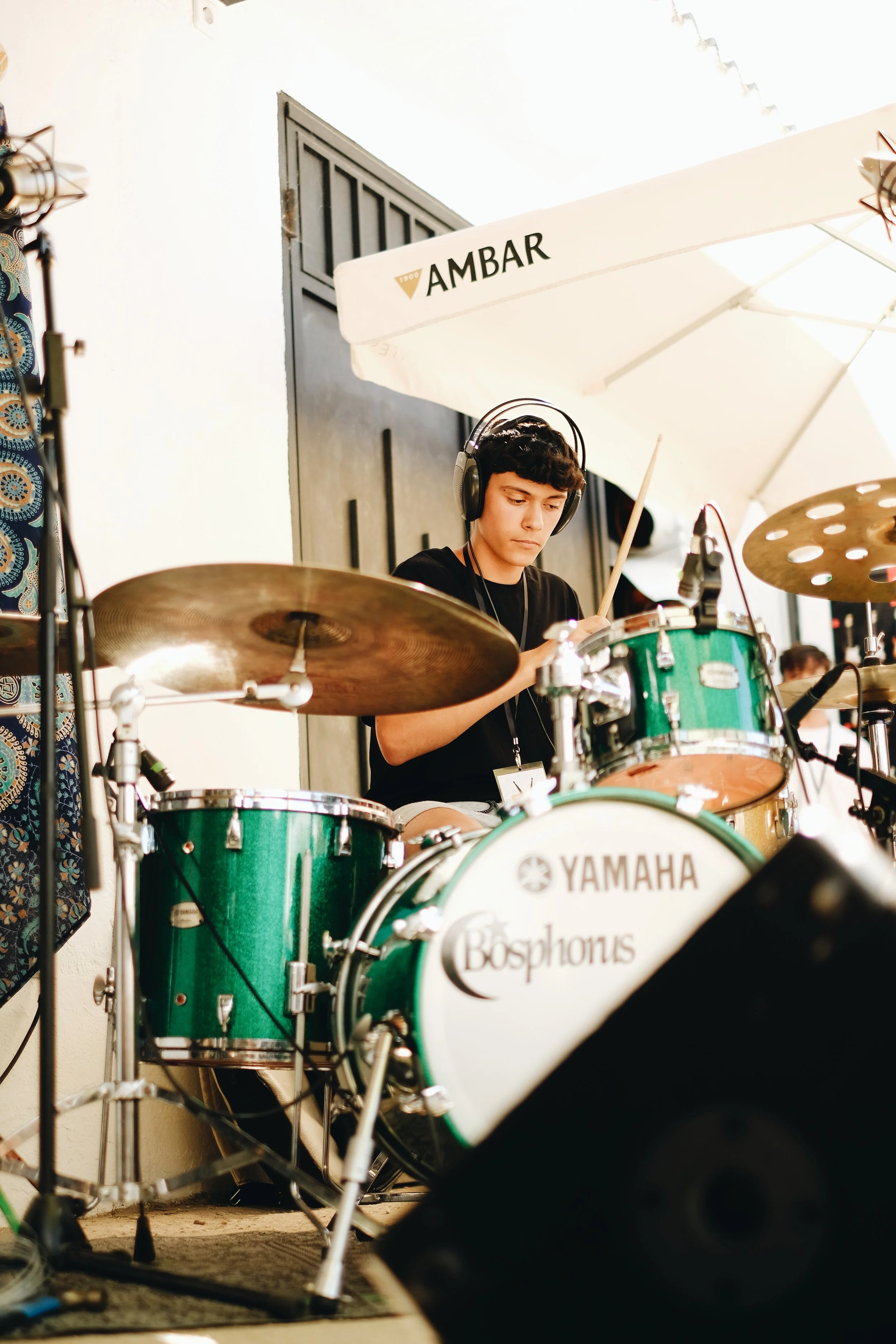 Joven tocando batería en un escenario con sombrilla