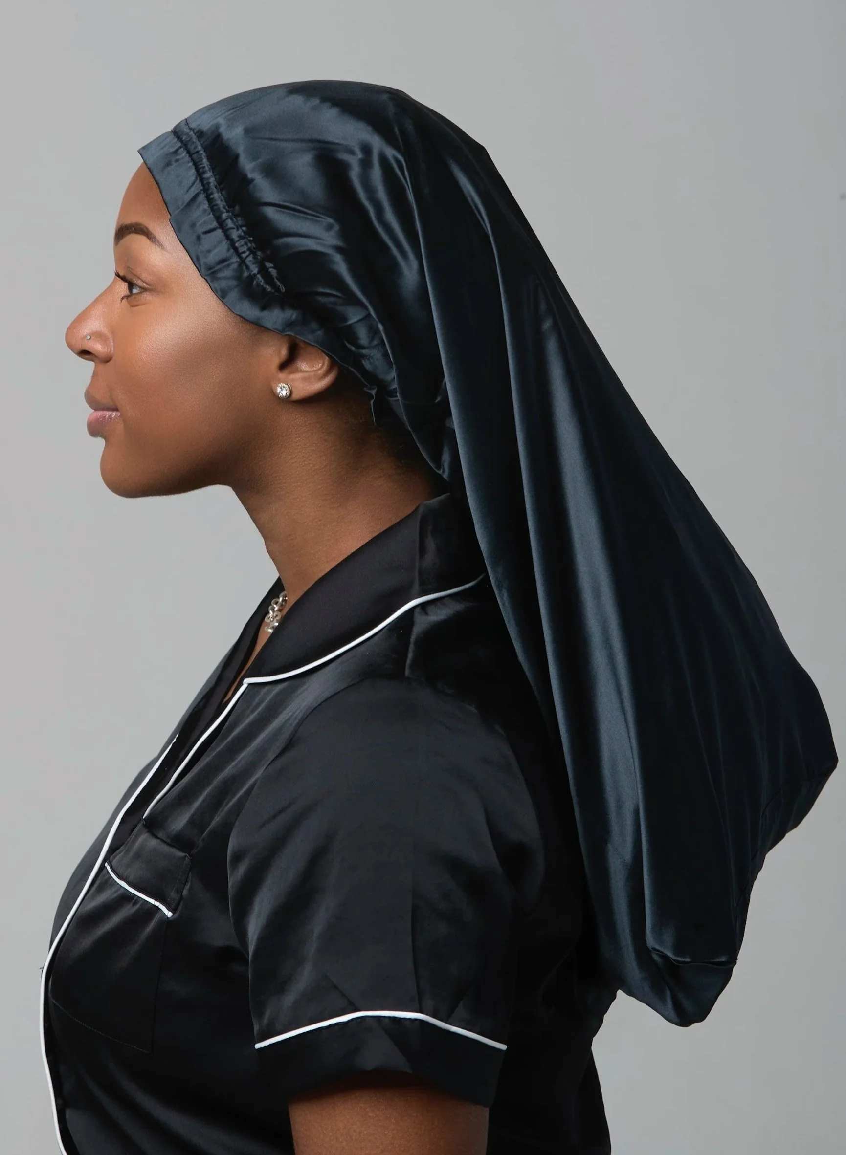 Woman wearing a black Select Silk bonnet made from 100% mulberry silk to help protect hair and reduce frizz.