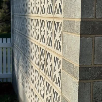Close-up of a decorative concrete block wall with a geometric pattern, next to a brick wall.