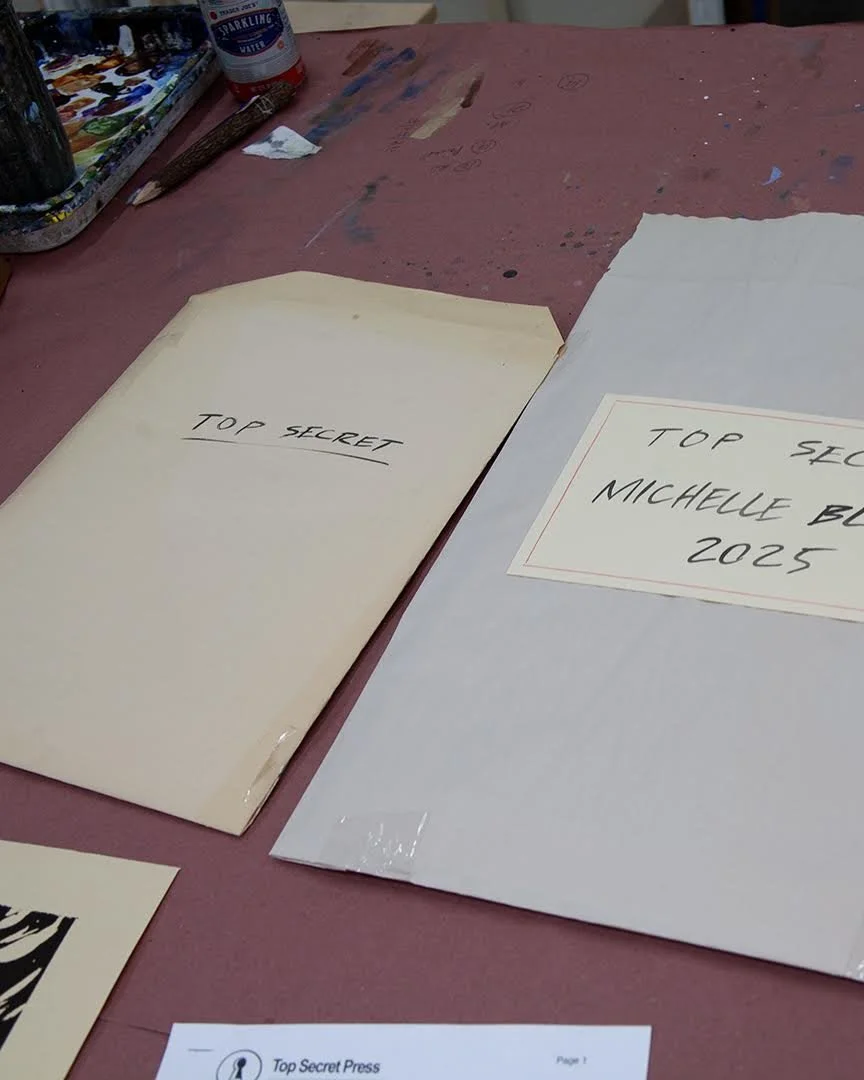 Two folders or envelopes labeled "TOP SECRET" on a cluttered, pink-painted worktable.