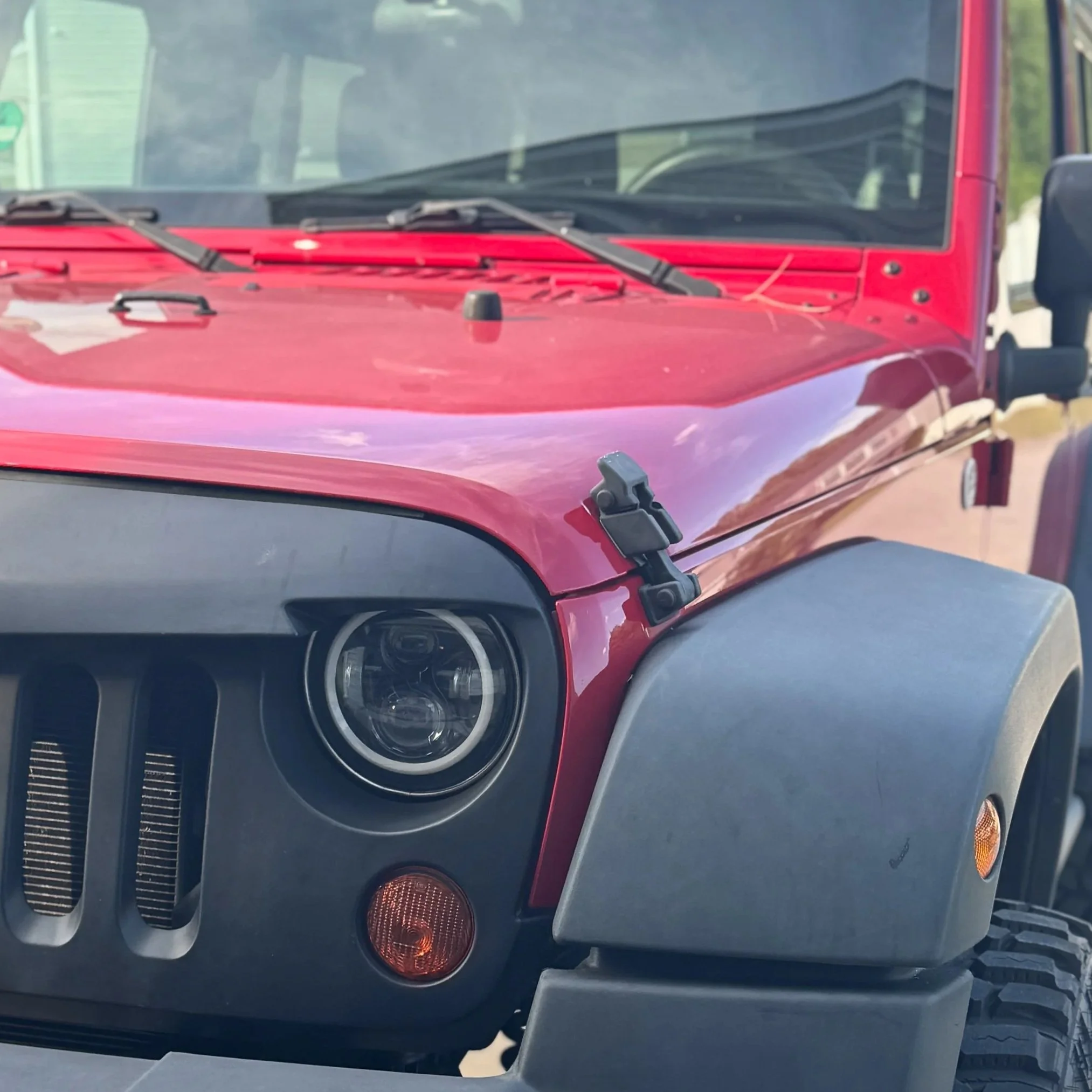 Red Jeep front grille and headlight cleaned during professional auto detailing service.