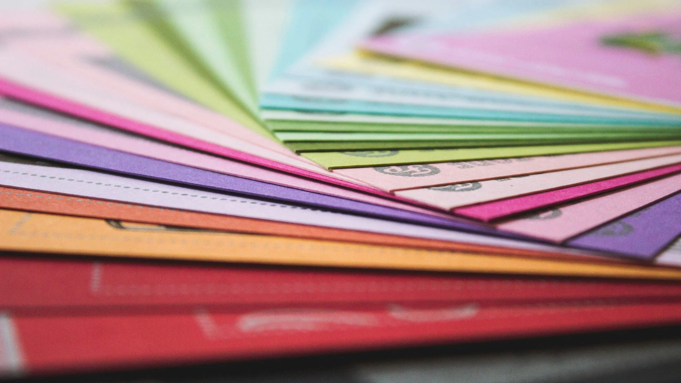 Close-up of colorful paper bills fanned out, featuring shades of pink, purple, green, orange, and blue.