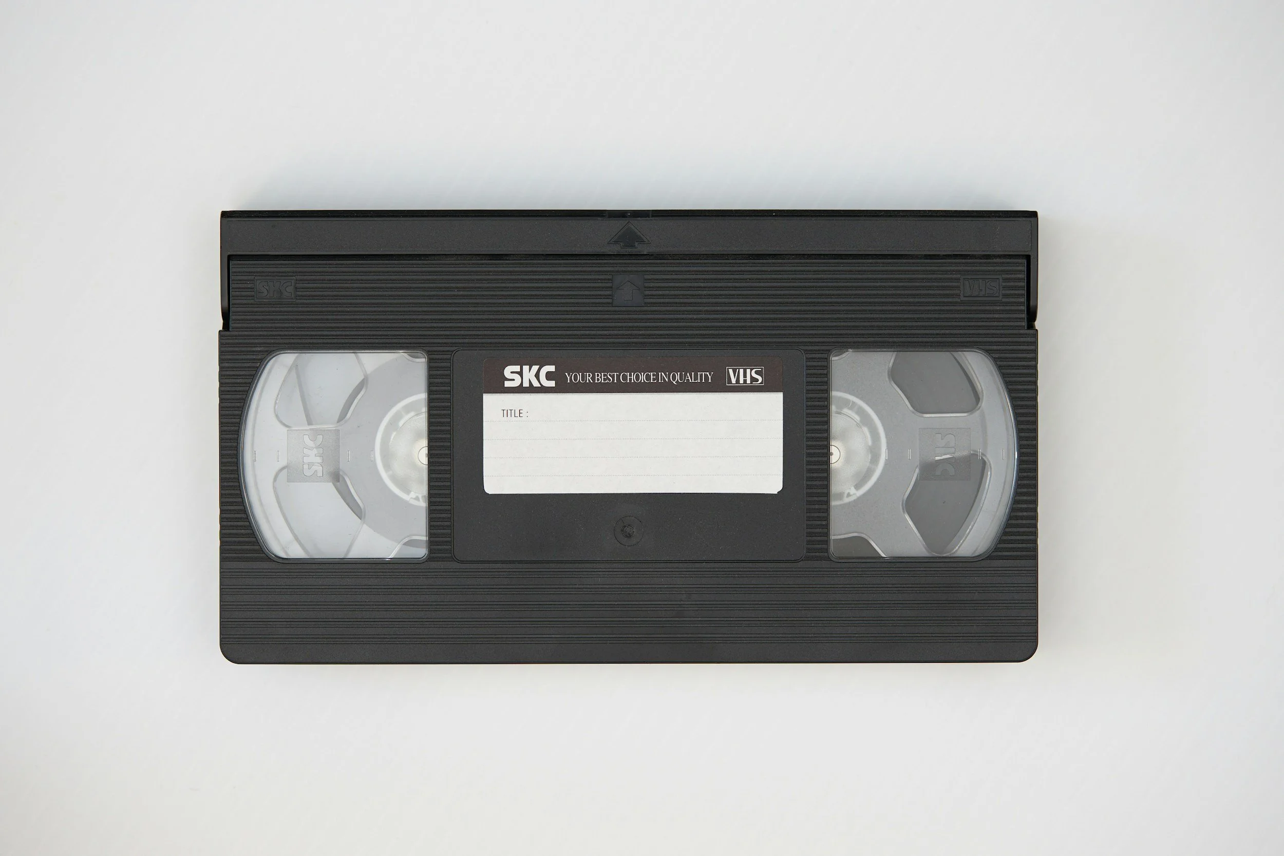Black VHS cassette tape with white label and transparent windows on a white background.