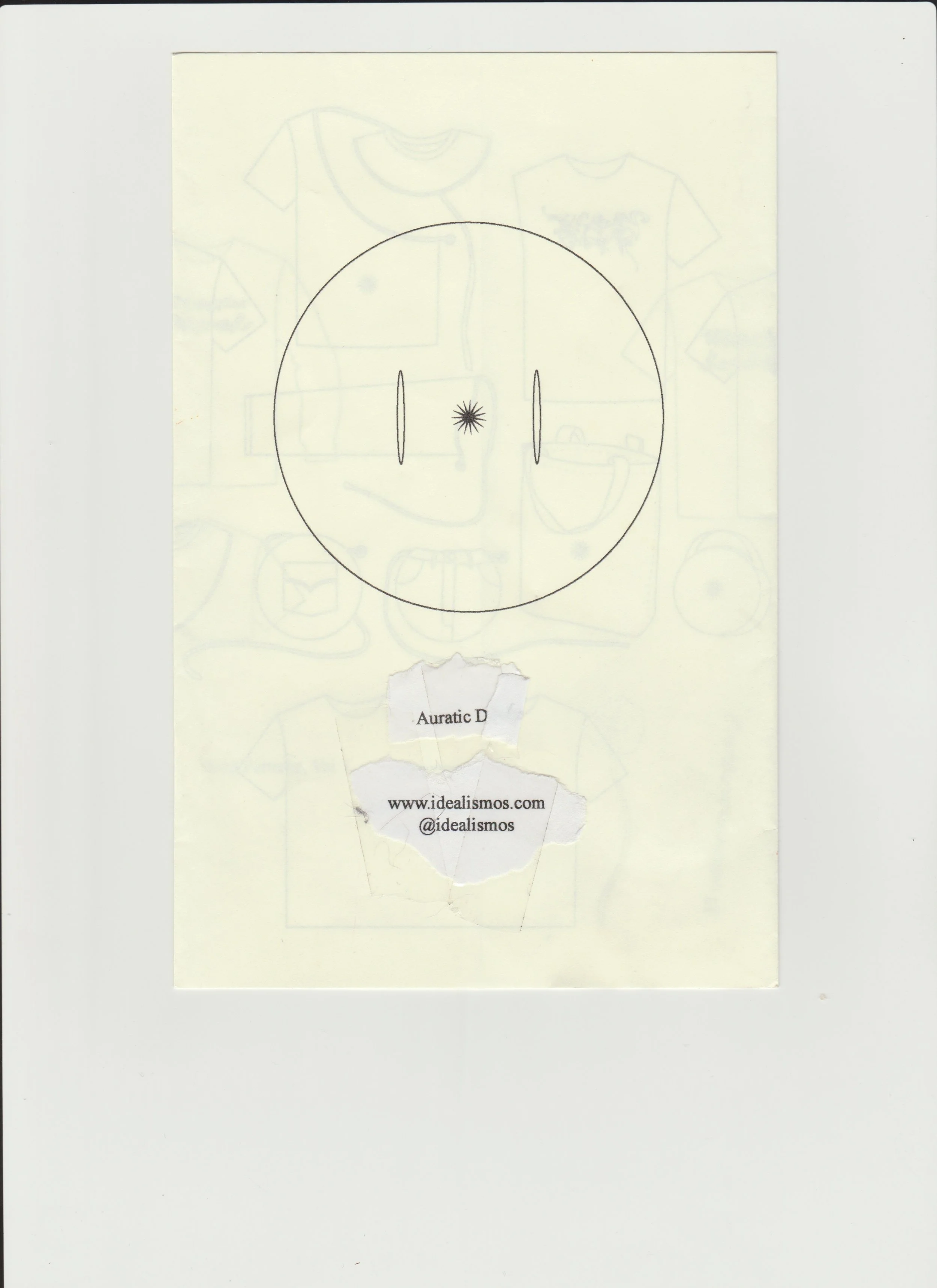 A circular diagram with two vertical oval shapes and a small star-shaped symbol in the center, with torn paper below displaying text: "Auratic D" and a website URL, www.idealisimos.com, with a social media handle @idealismos.