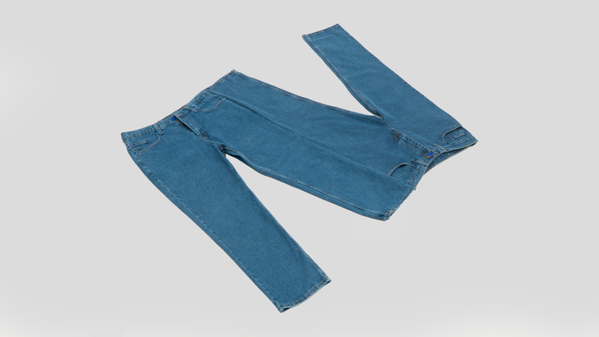 Blue pair of jeans laid out flat on a light gray background.