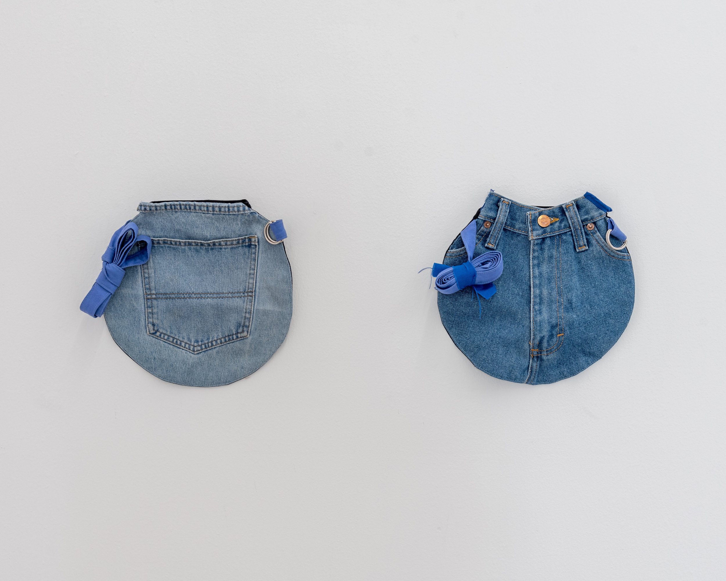 Two small denim purses with blue ribbon bows, placed on a white background.