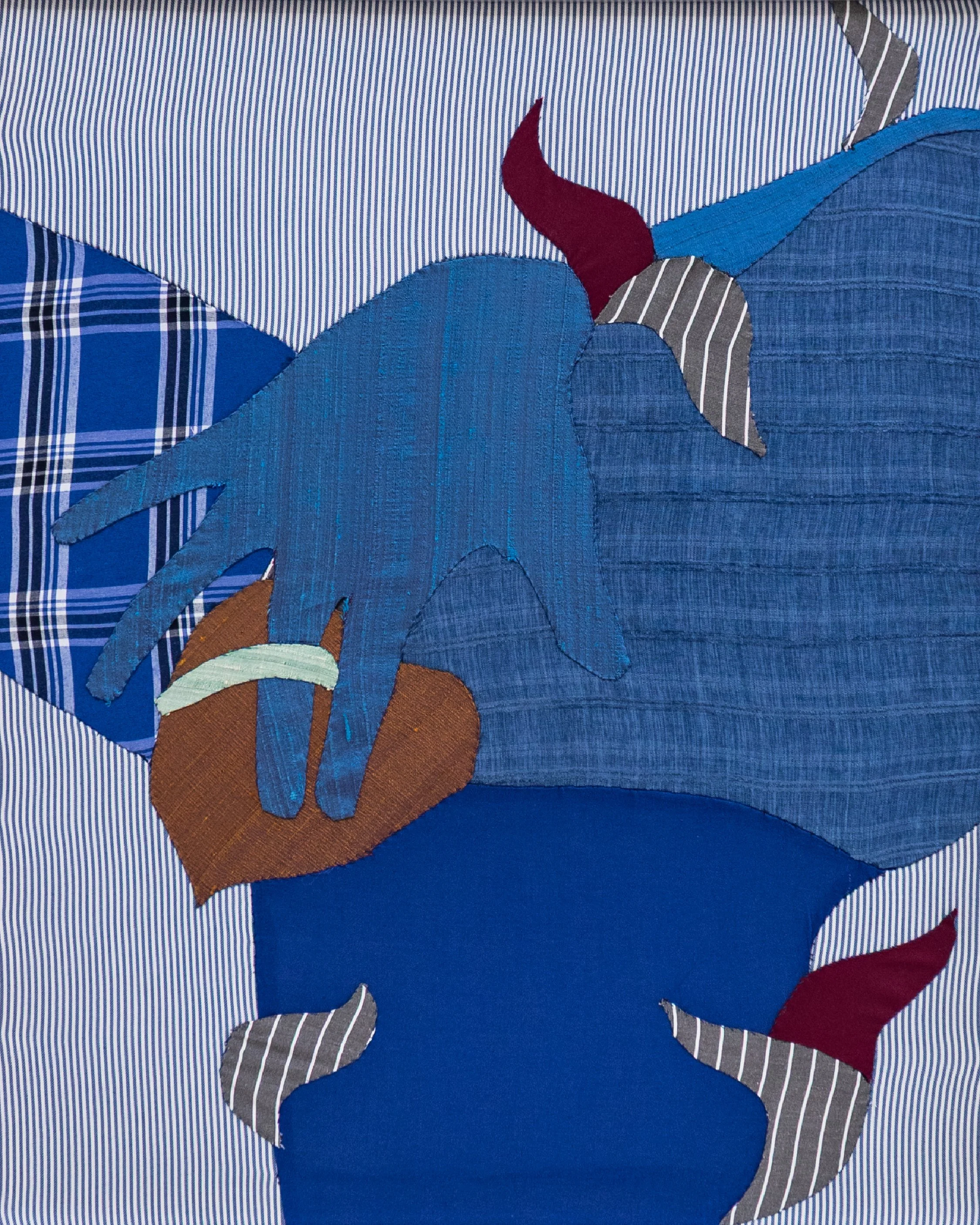 A quilted fabric artwork featuring a blue horse with a red mane, standing on an orange patch, against a background of various blue and stripped fabrics.