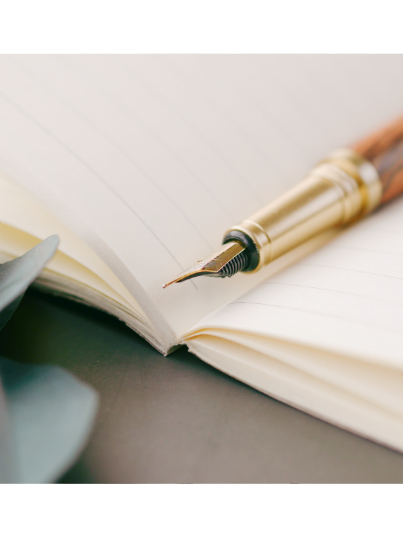 A fountain pen resting on an open lined notebook.