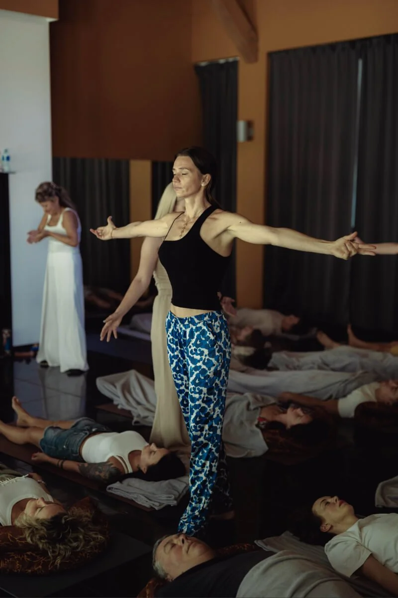 Women practicing energy work indoors on mats with eyes closed in a peaceful setting.