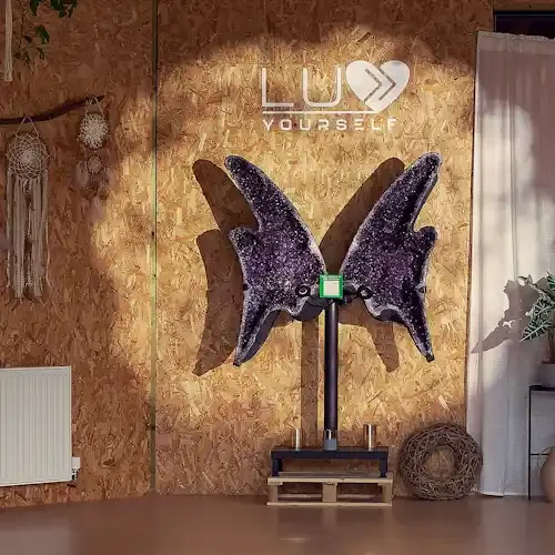 Large amethyst crystal with light shining on it and sign luv yourself space