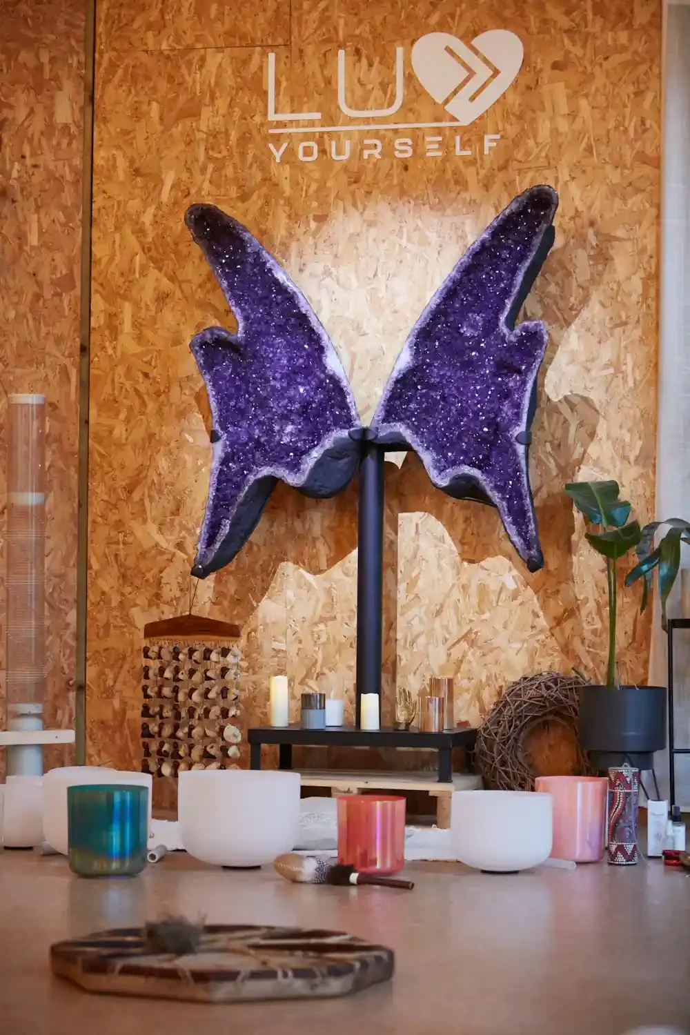 Large amethyst crystal and music instruments in a calm space with plants around and candles.