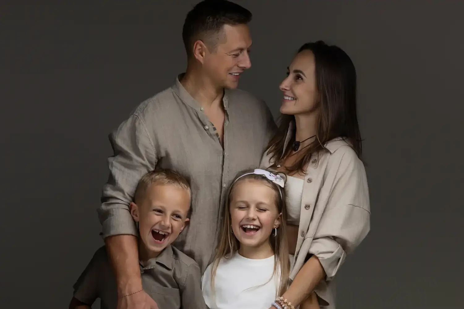 A happy family of four are looking at each other and smiling.